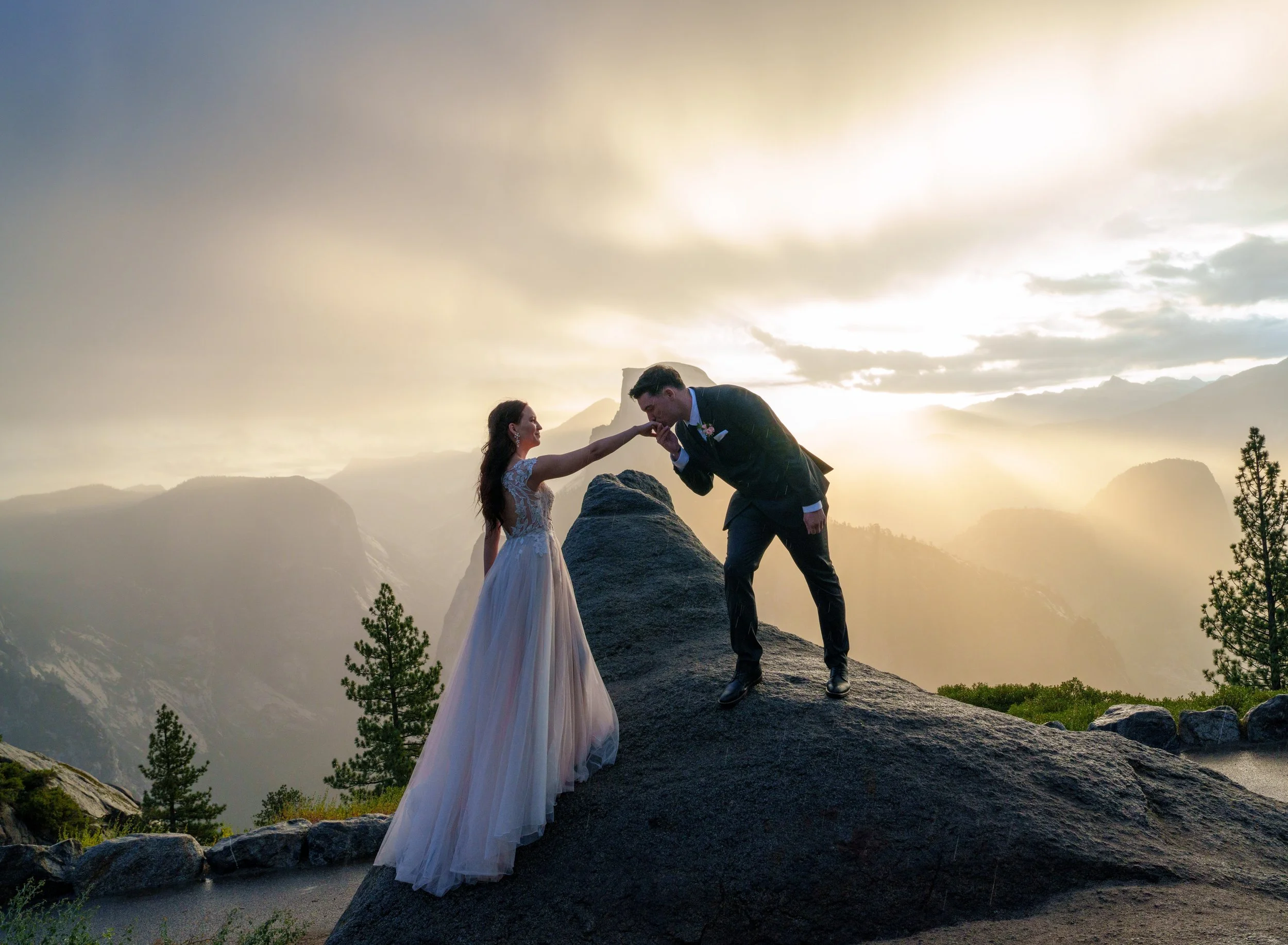 A bride and groom exchanging wedding vows on a rocky ledge with mountains and a cloudy sky in the background, during sunset or sunrise. Yosemite Elopement Videography Yosemite Nation Park. Yosemite Elopement Photography. 