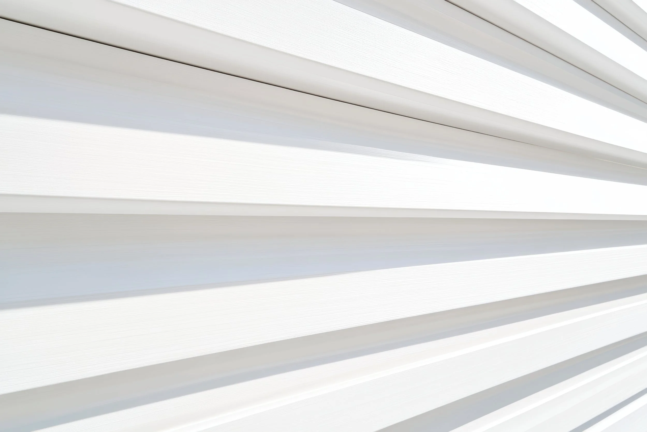 Close-up of white horizontal window blinds with sunlight filtering through.