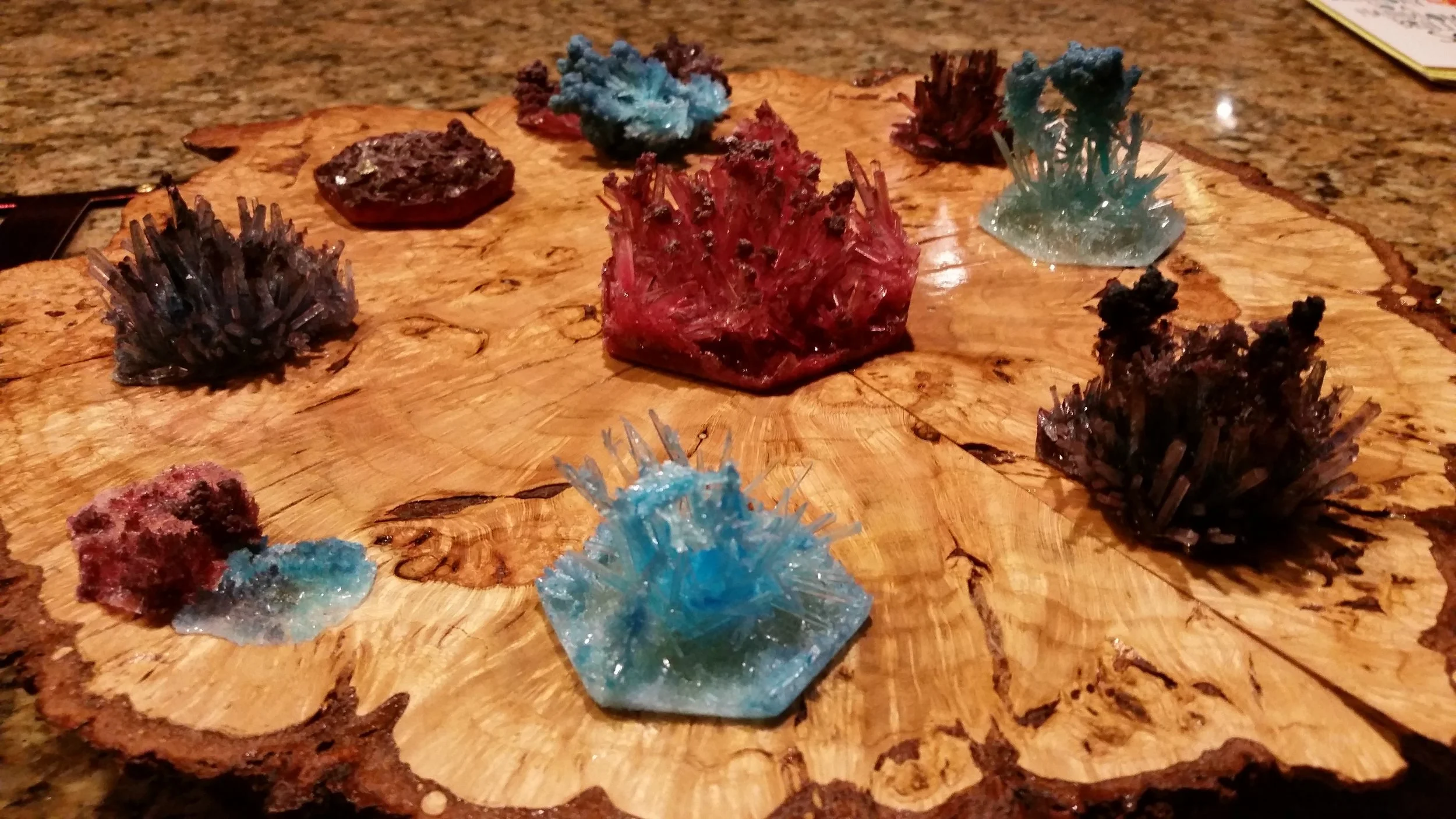 Collection of colorful mineral or crystal specimens on a wooden display board.