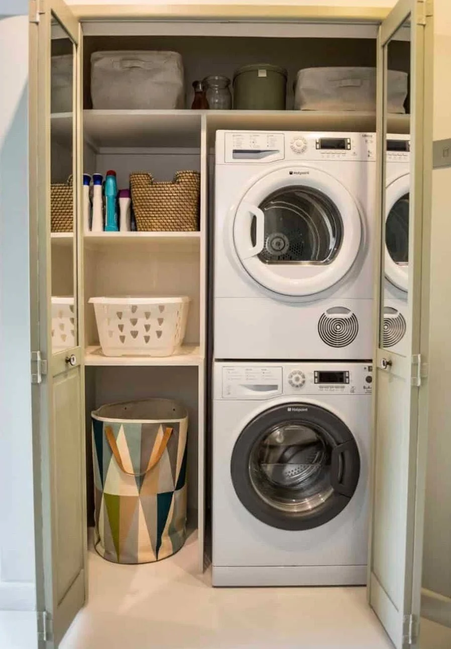 Closet with laundry appliances and storage shelves, containing a washing machine, a dryer, laundry baskets, and cleaning supplies.
