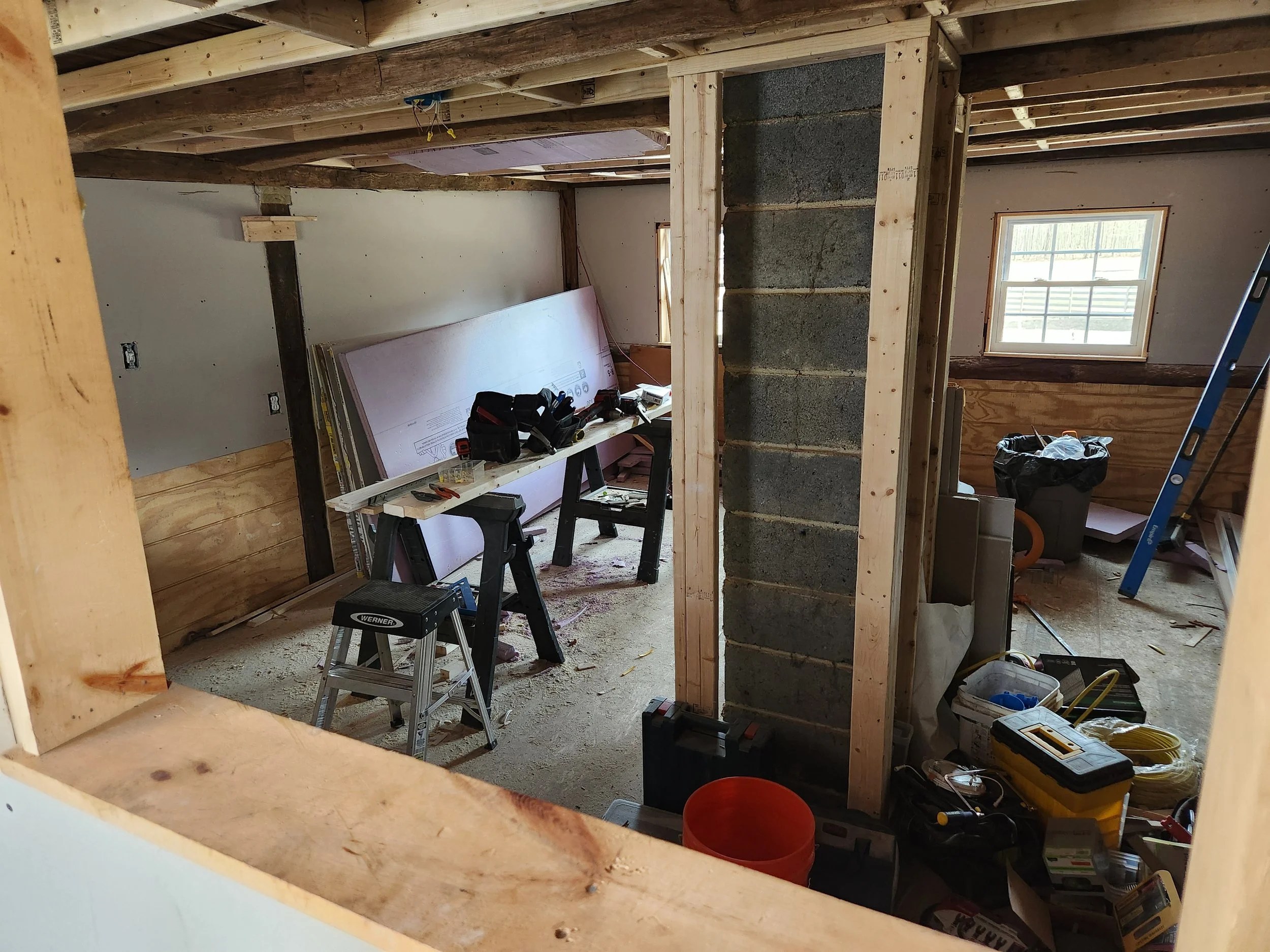 Room under construction with exposed framing, tools, and building materials.