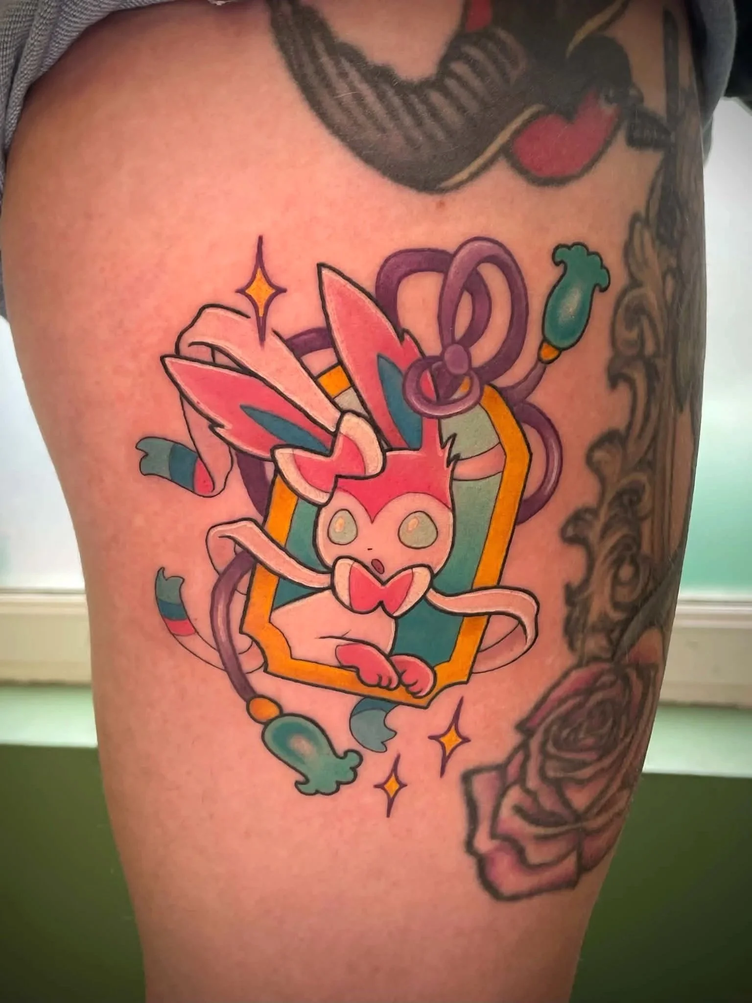 Colorful tattoo of a rabbit with snowdrops and stars on a person's upper arm.
