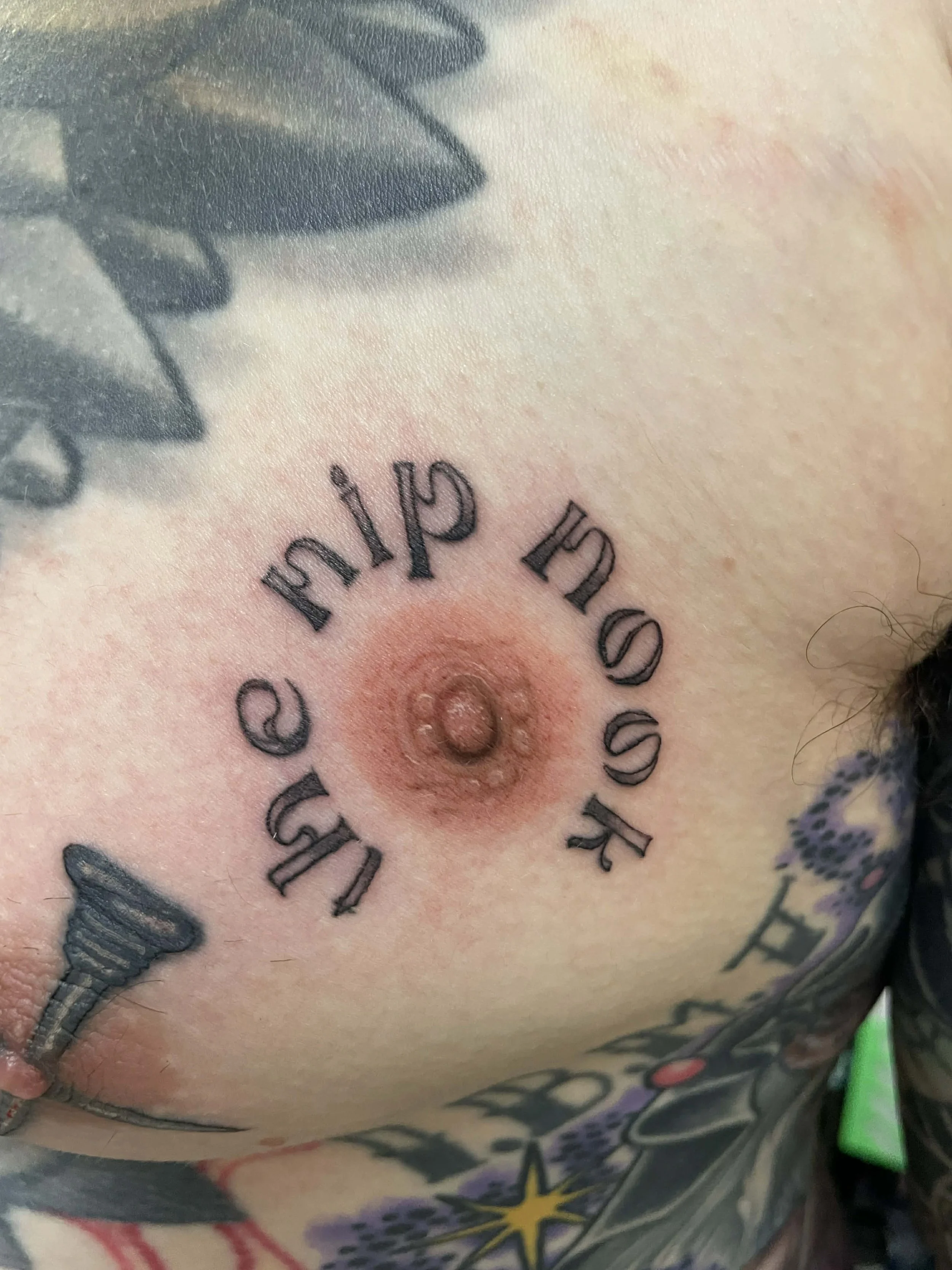 Tattoo of a ring of text that reads the nip nook around an Areola tattoo after the second session 