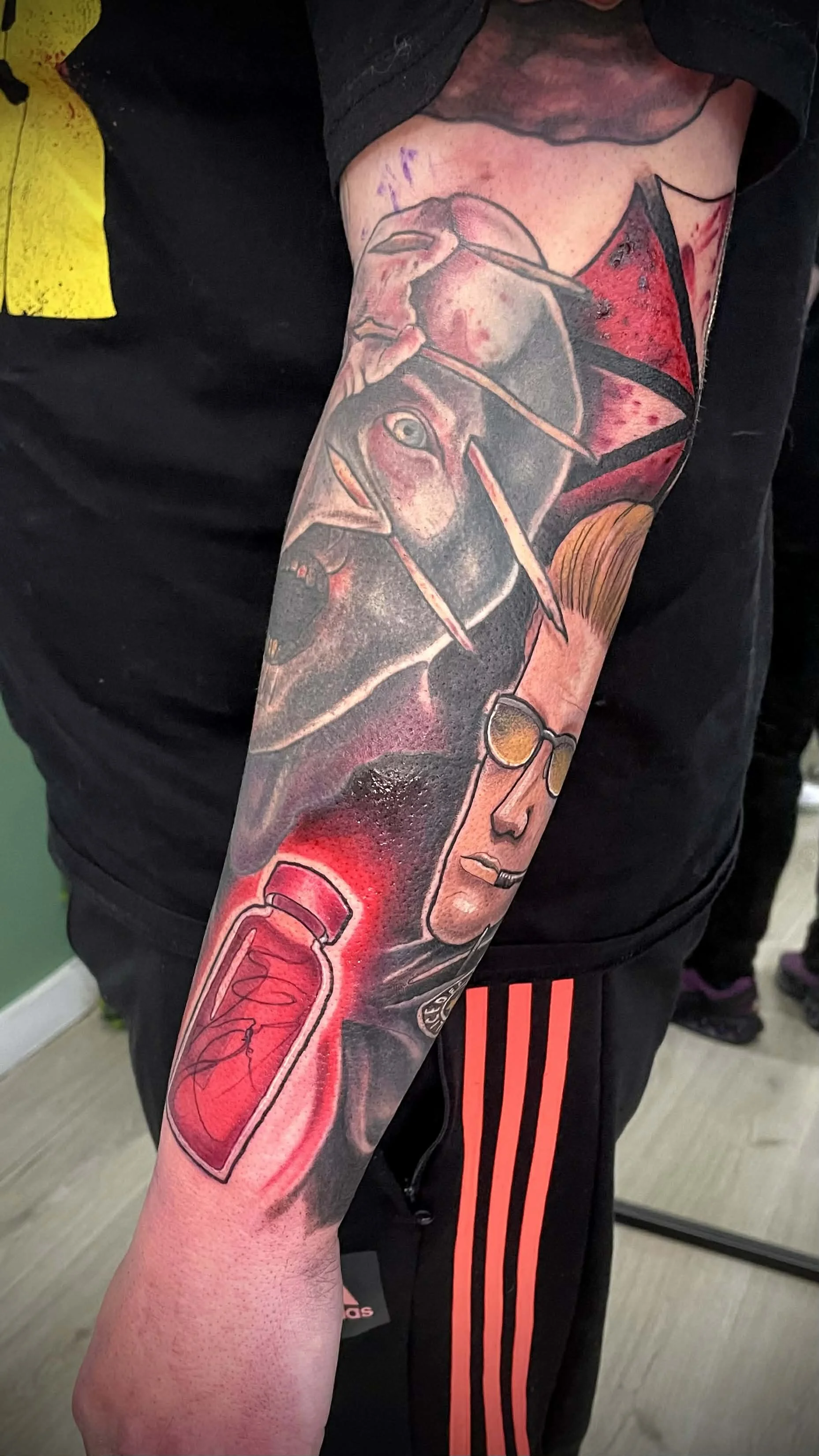 Tattoo sleeve featuring a rock star, a dog with a paintbrush, a blood vial, and various abstract elements. Resident evil 