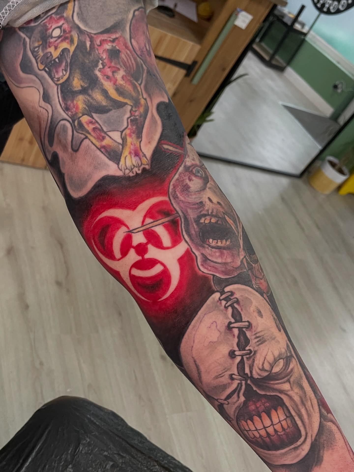 Tattoo sleeve featuring a dog with its mouth open, a biohazard symbol, and a skull with an open mouth.