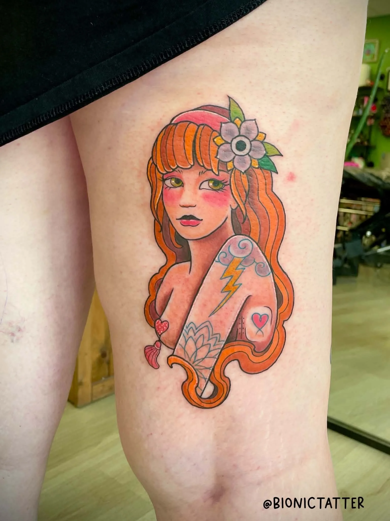 Colorful tattoo of a woman with orange hair, flowers, hearts, a lightning bolt, and a star on her arm, located on the thigh.