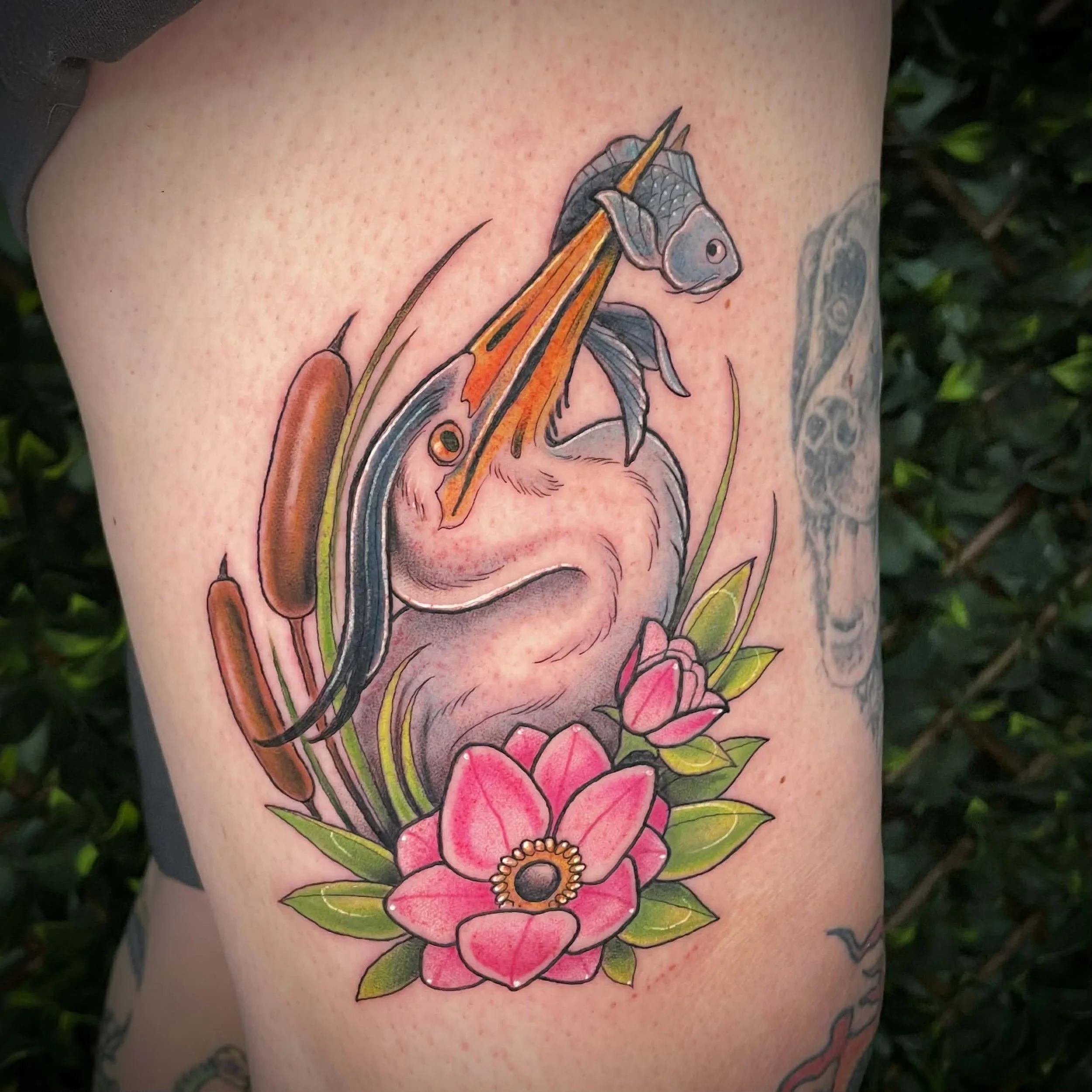 Colorful tattoo of a heron carrying a fish with flowers and greenery.