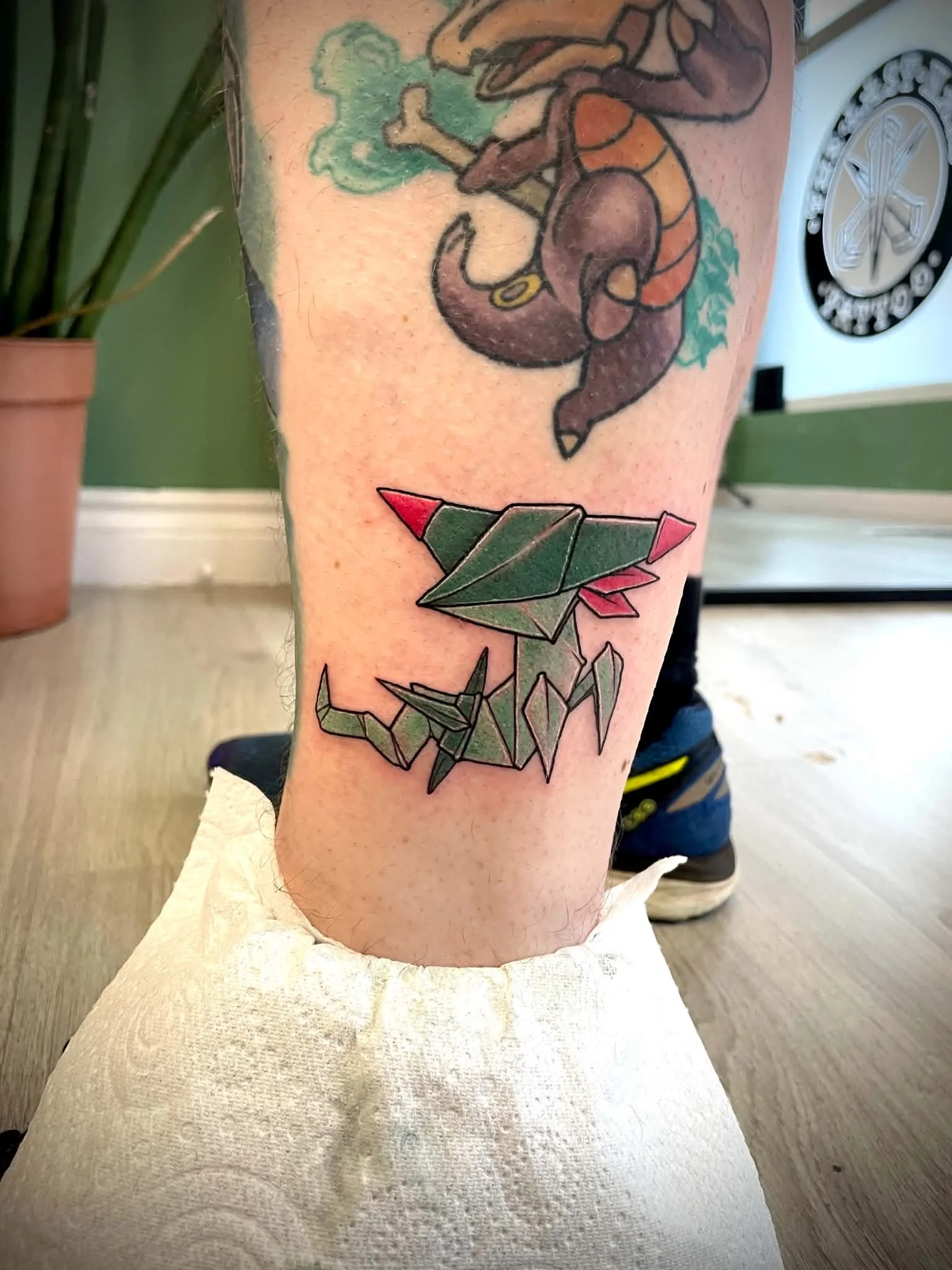Tattoo of a ookemon, creepy with a green background on person's upper arm.