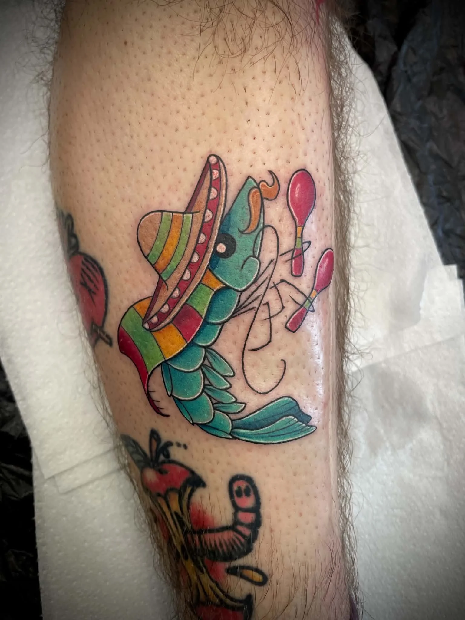 Colorful tattoo of a mexican shrimp with rainbow stripes on a person's arm.