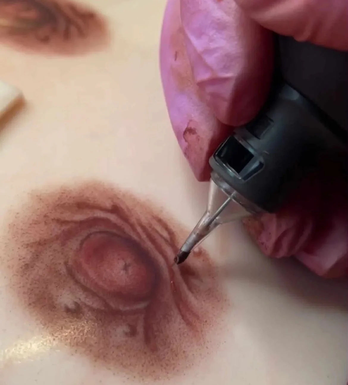 Close-up of a tattoo artist using a tattoo machine to ink a circular 3d Areola design on skin.