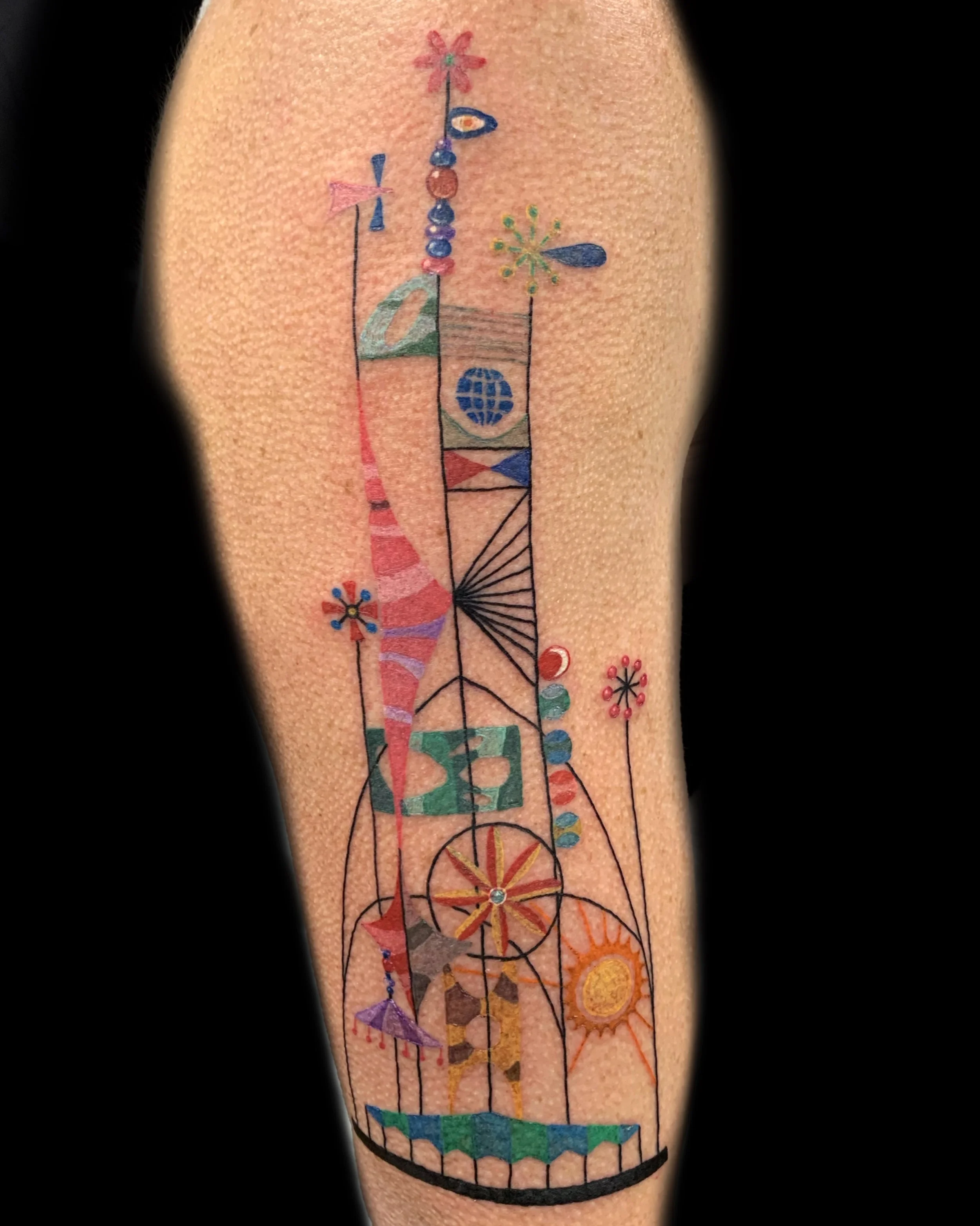 Colorful abstract geometric tattoo on arm with shapes, lines, and patterns.