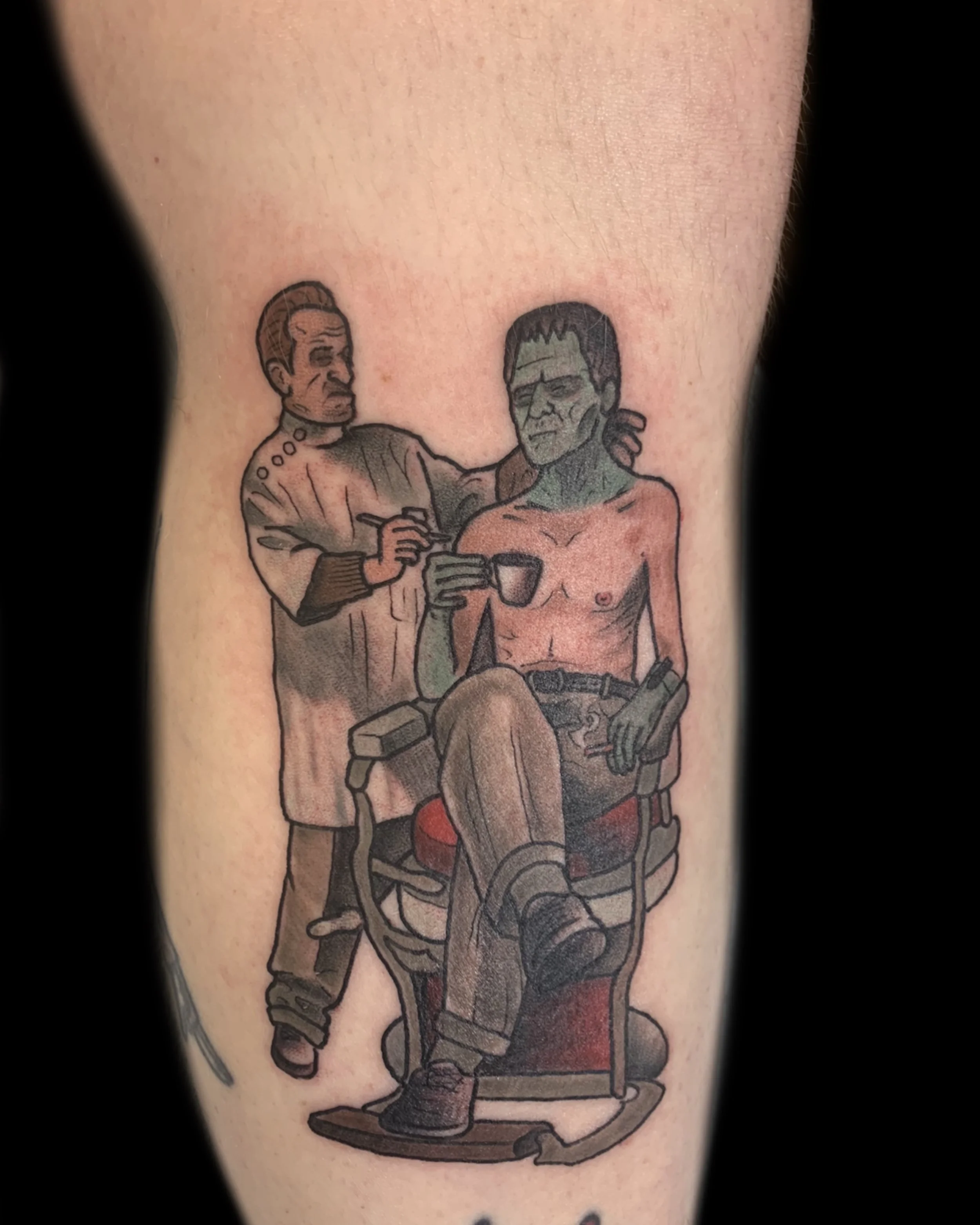Tattoo of a green zombie-like man with a gun sitting on a chair, while a nurse with a stern expression draws his blood.