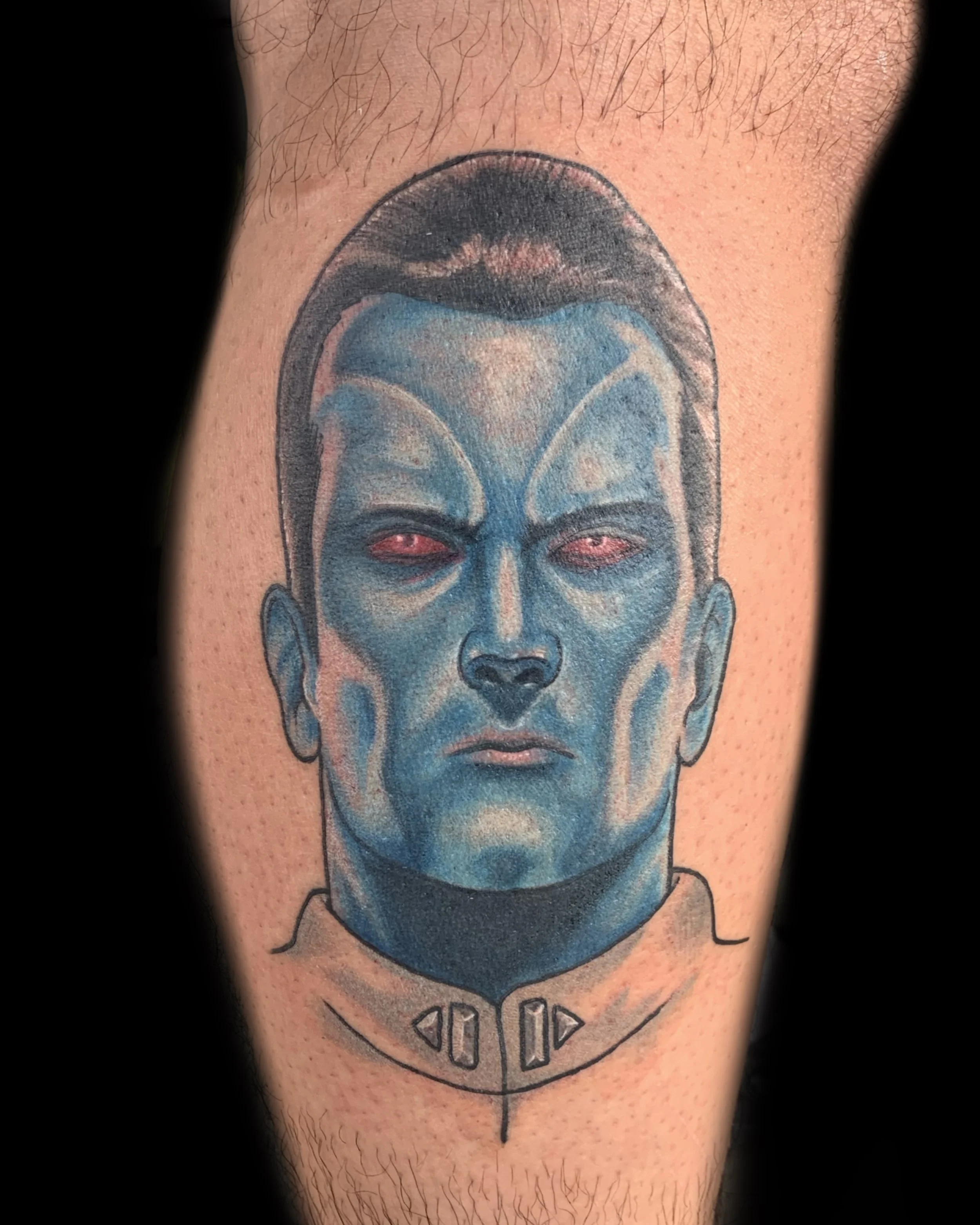 Tattoo of a character with blue skin, black hair, and red eyes, wearing a futuristic collar with buttons.