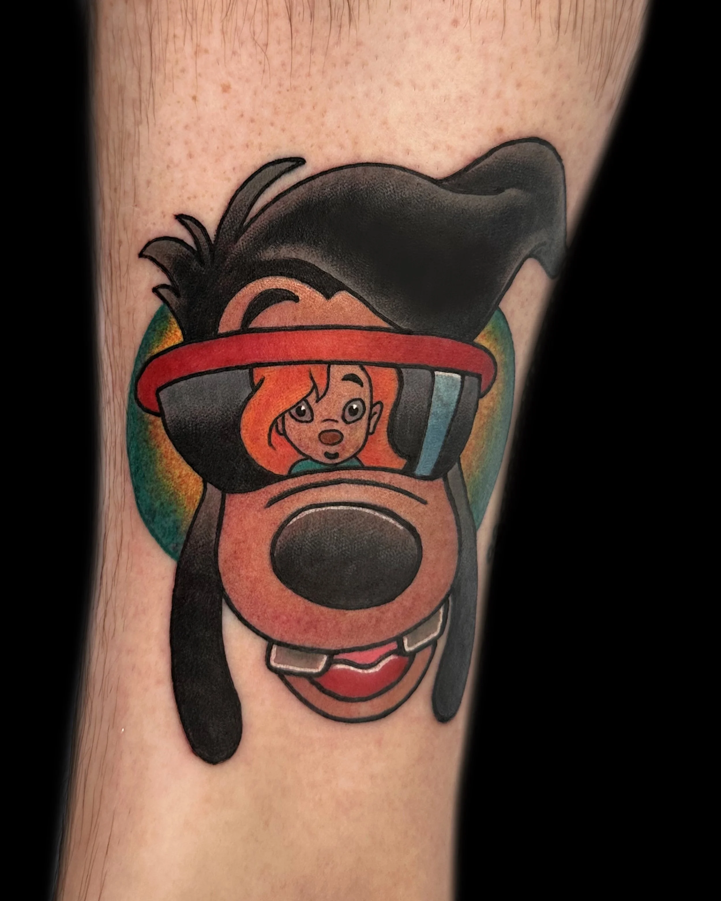 Tattoo of a cartoon dog with a red floppy hat and long ears, with a clown face, smiling with cheeks and teeth visible.