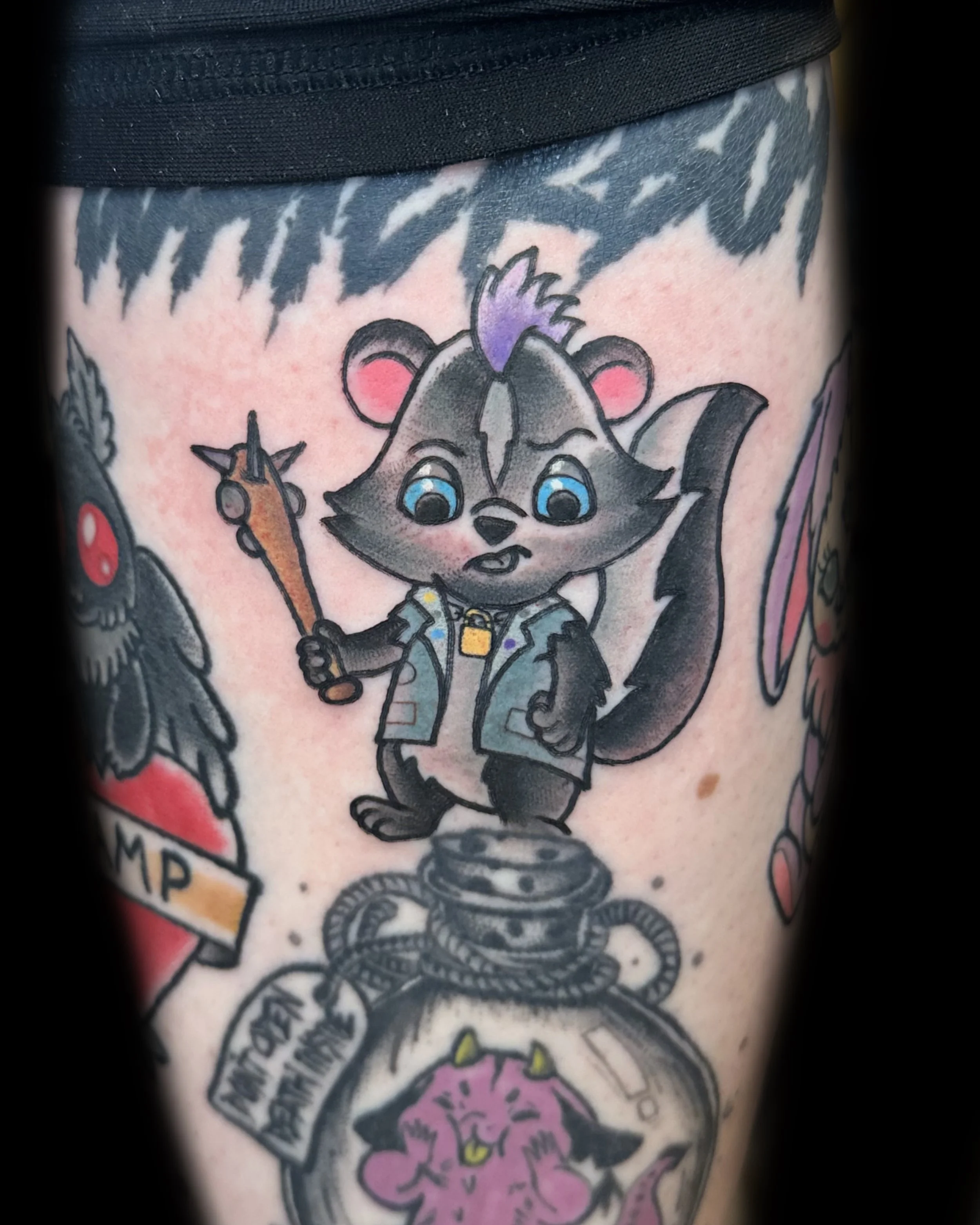 Tattoo of a cartoon raccoon wearing a jacket, holding a knife, standing on a bomb with a defused timer.