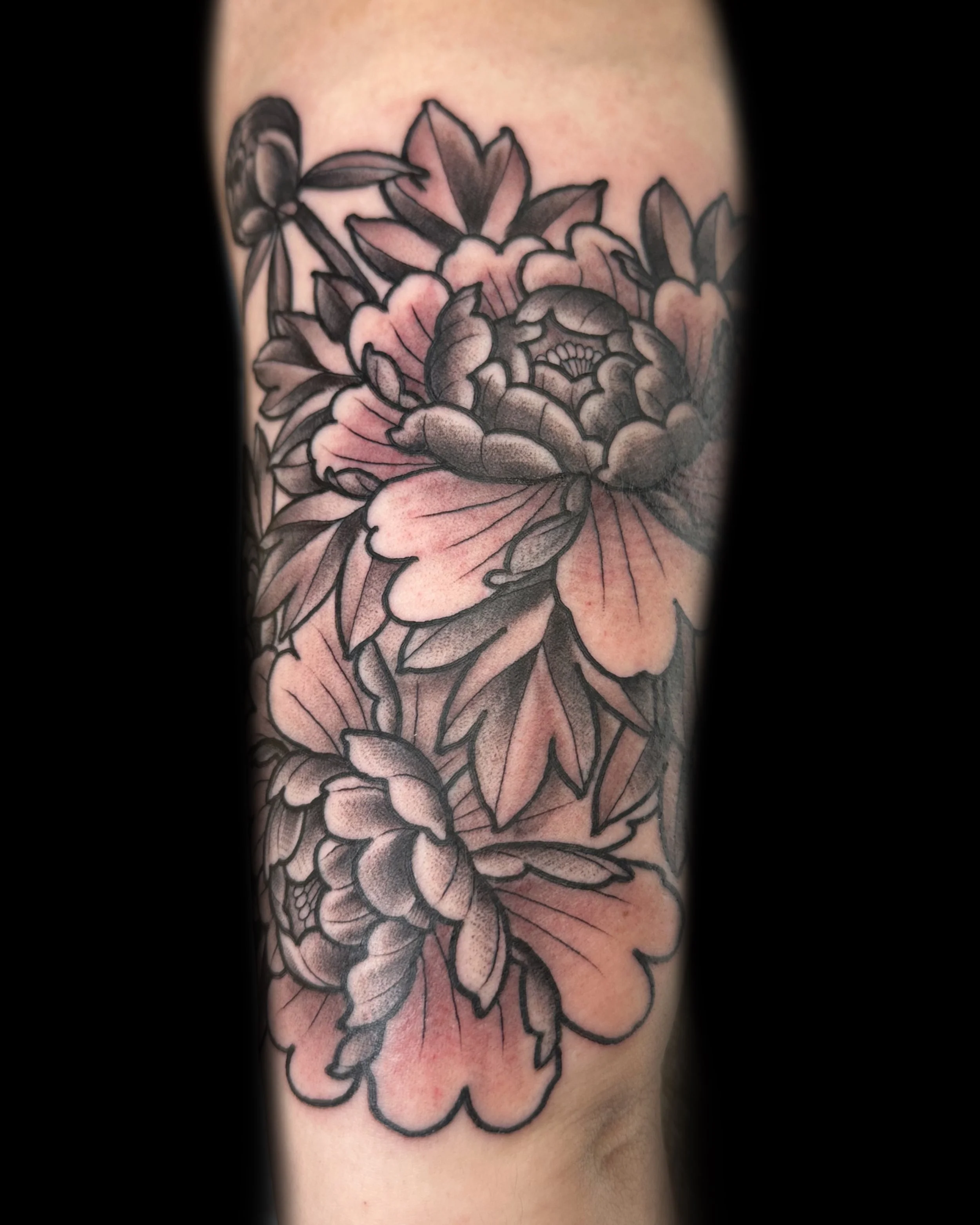 Clean black and grey floral tattoo on arm. Crisp details. Vegan tattooer, climbing tattooer, van-life tattooer.