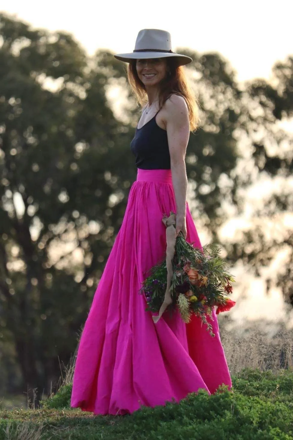 Jamila Hume standing in a field of wildflowers holding a native Australian bouquet