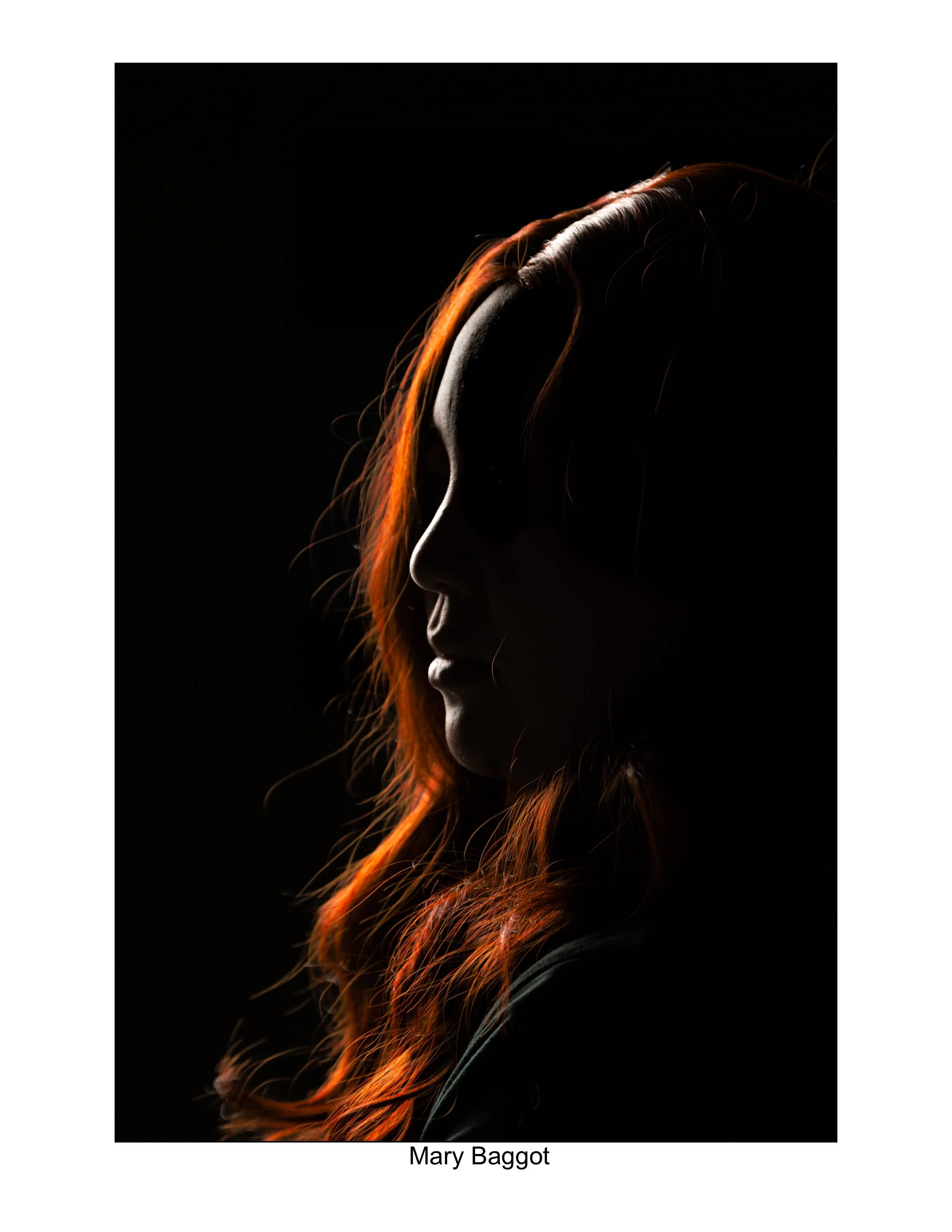 Silhouette of a Hmong woman with long red hair against a dark background. Backlight photography.