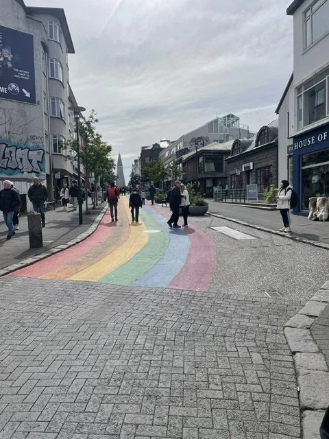 Rainbow-painted Skólavörðustígur leading through central Reykjavík toward Hallgrímskirkja.