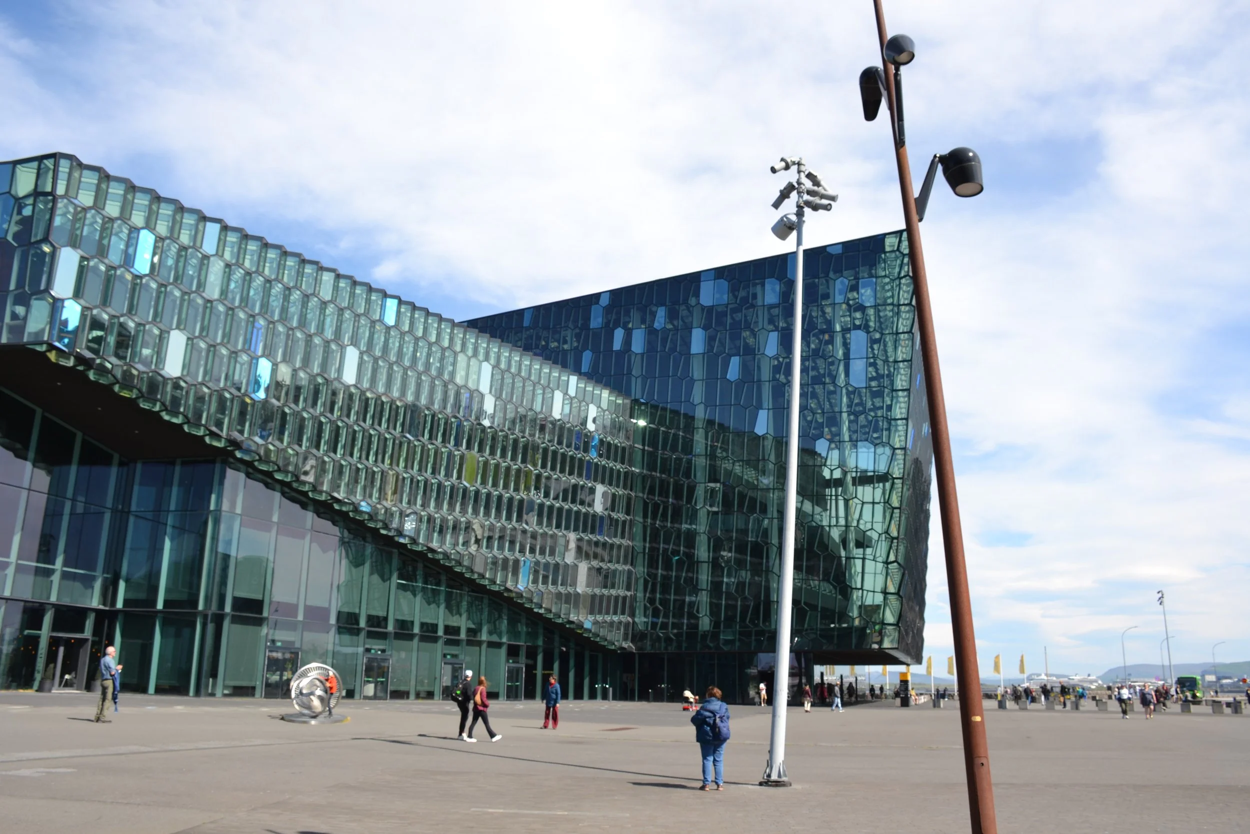 Geometric glass façade of Harpa Concert Hall reflecting the blue sky above its Reykjavík plaza.