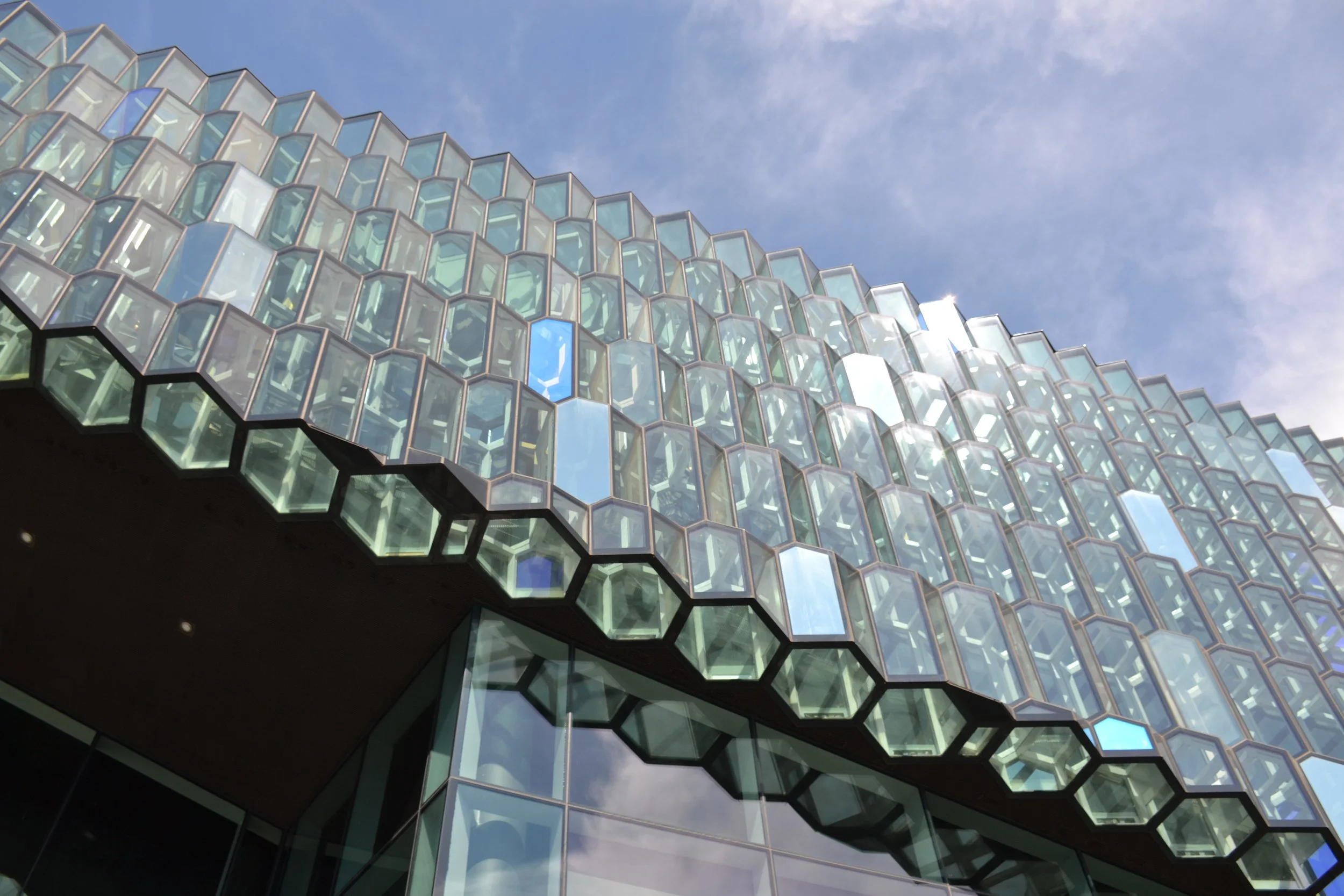 Close view of Harpa Concert Hall’s projecting glass quasi-bricks beside its flatter patterned façade.