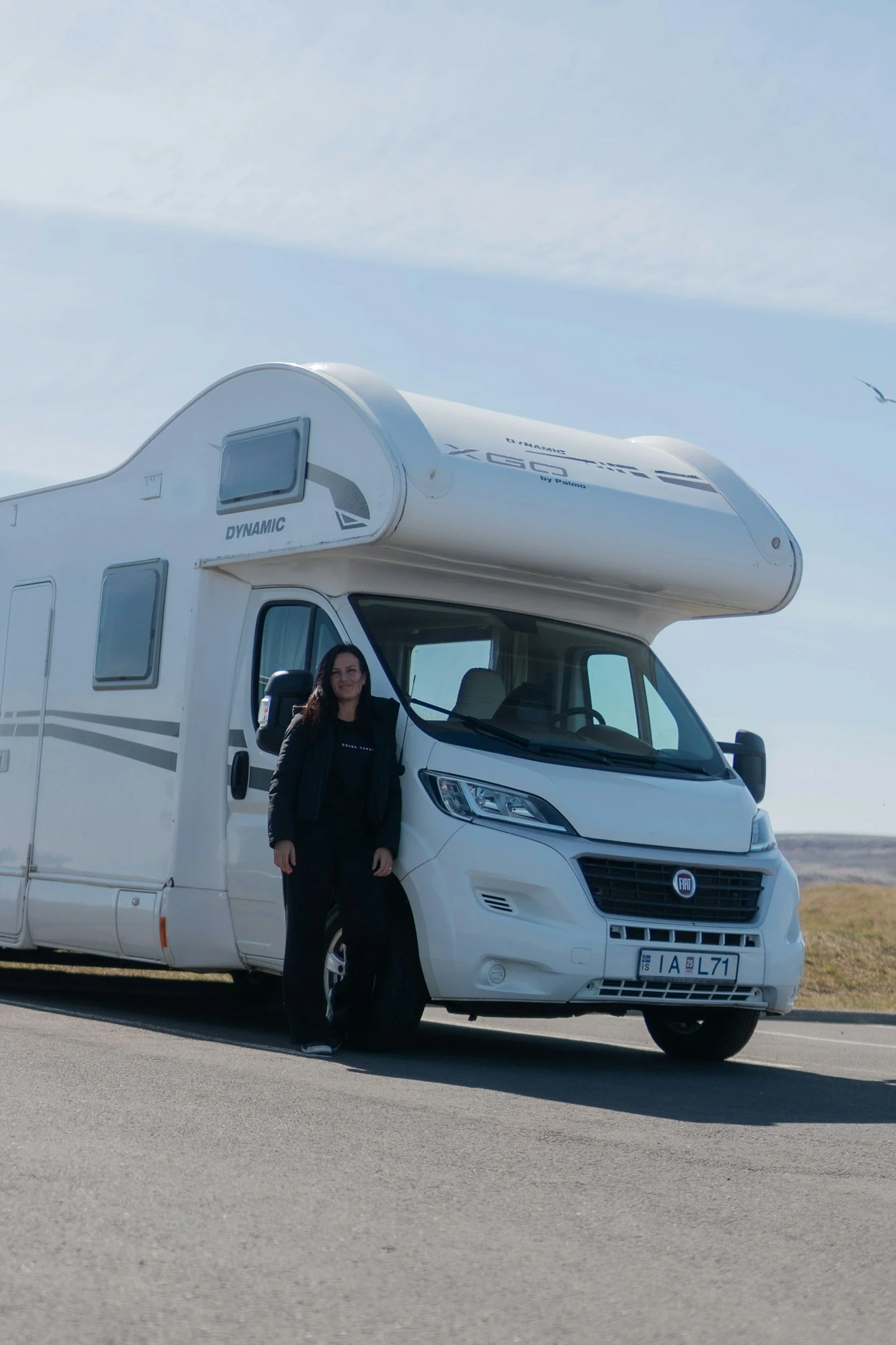 a woman stands next to her campervan