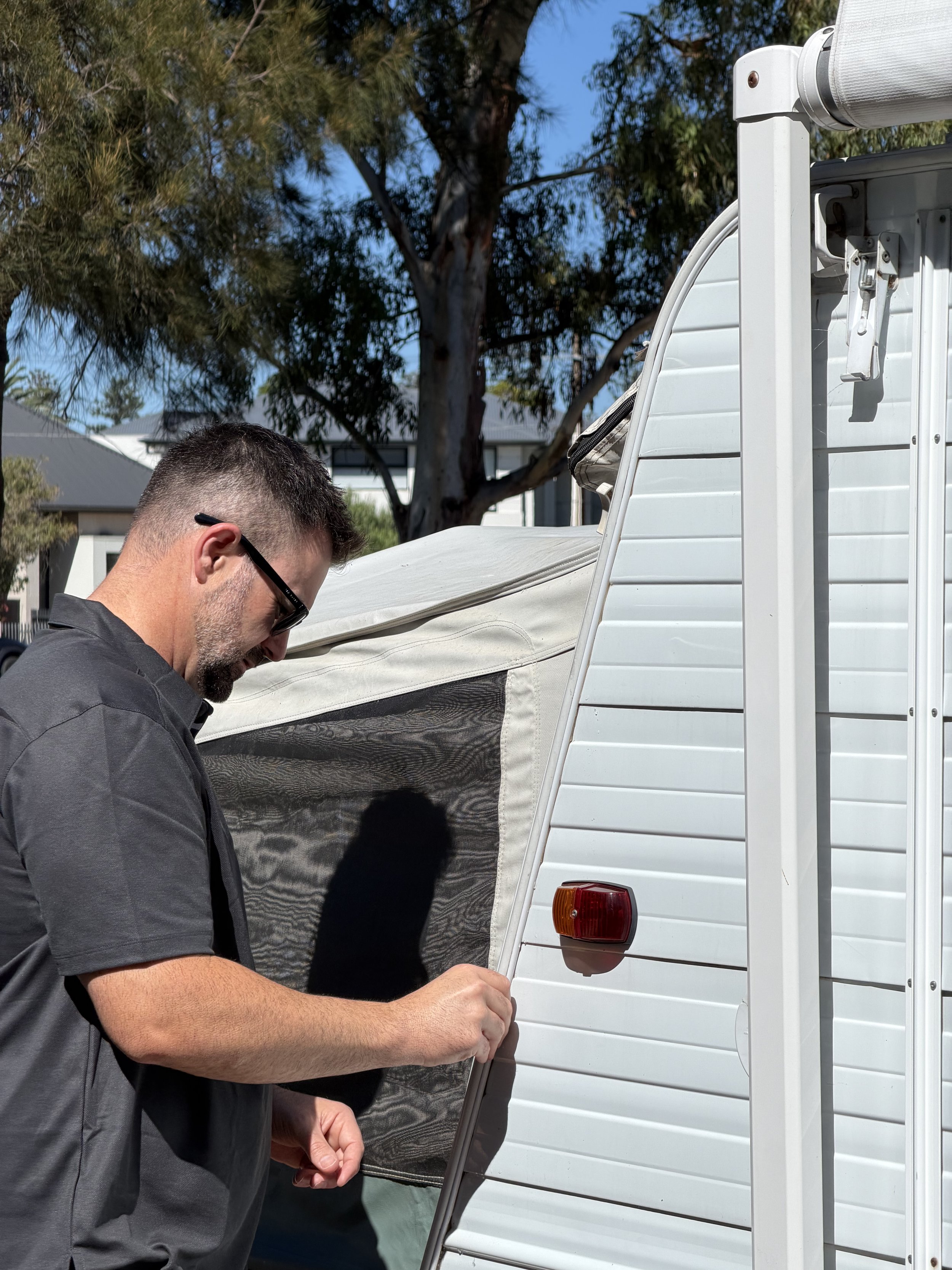 Man in polo shirt assesses water damage on a caravan