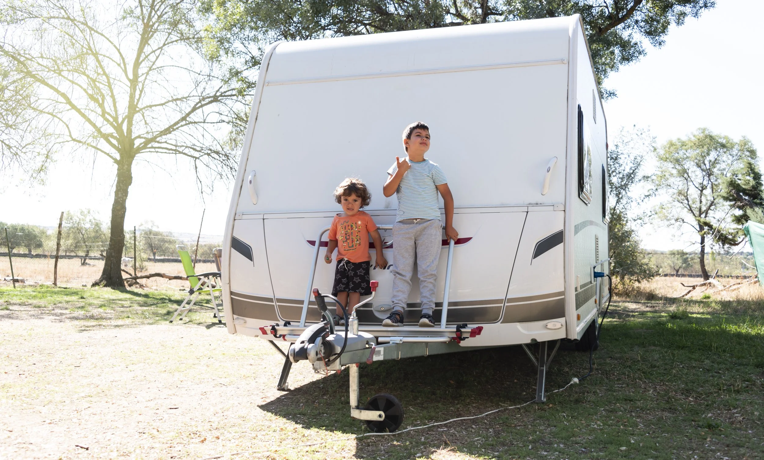 two children play outside their family caravan