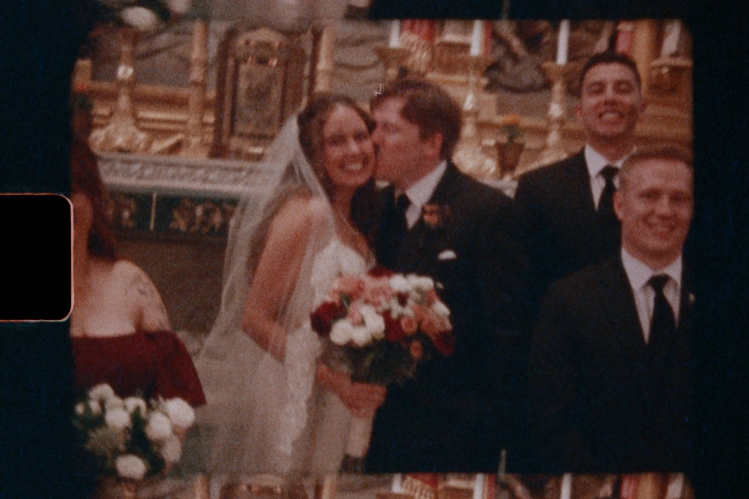 A wedding kiss between a bride and groom surrounded by cheering guests in a church.