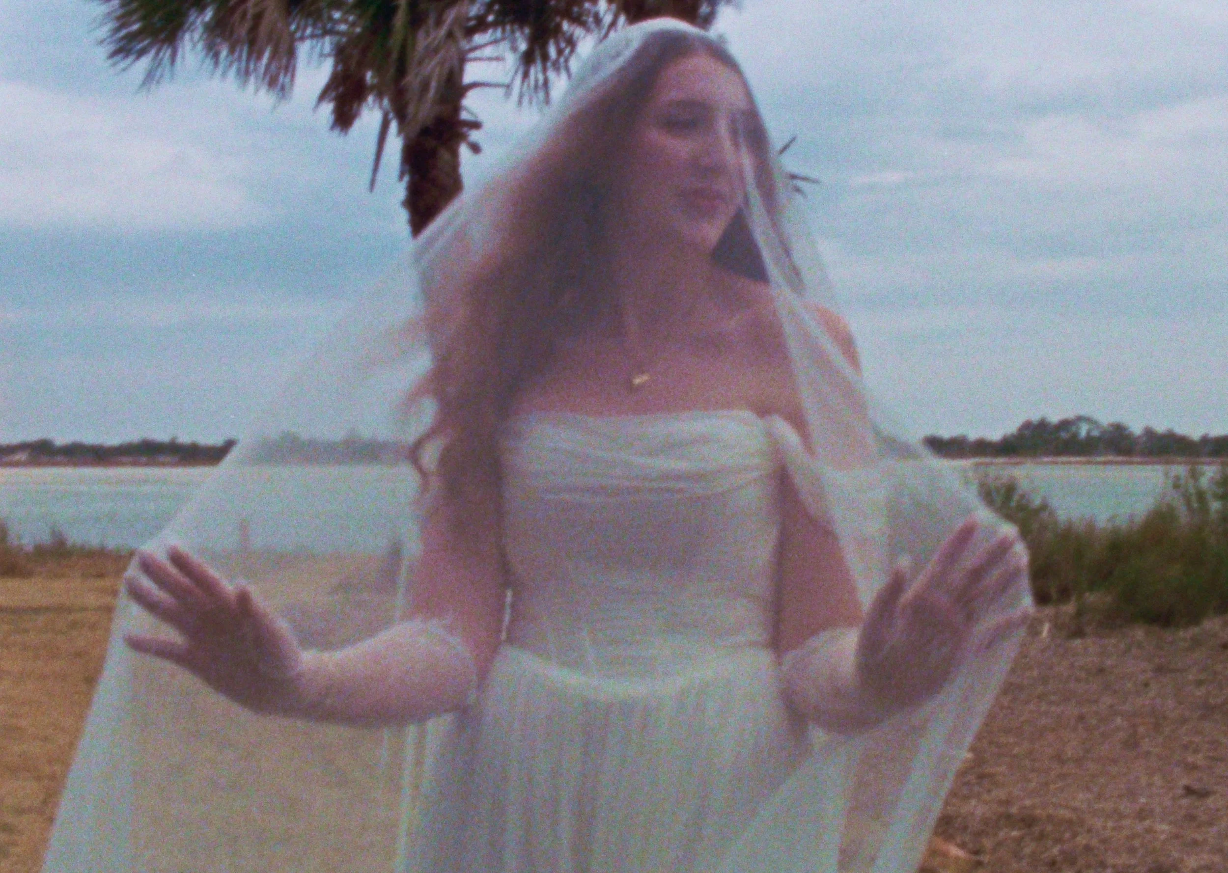 A man and woman exchanging flowers in a formal setting, with the man holding a bouquet of light-colored flowers and the woman smiling while wearing a black outfit.