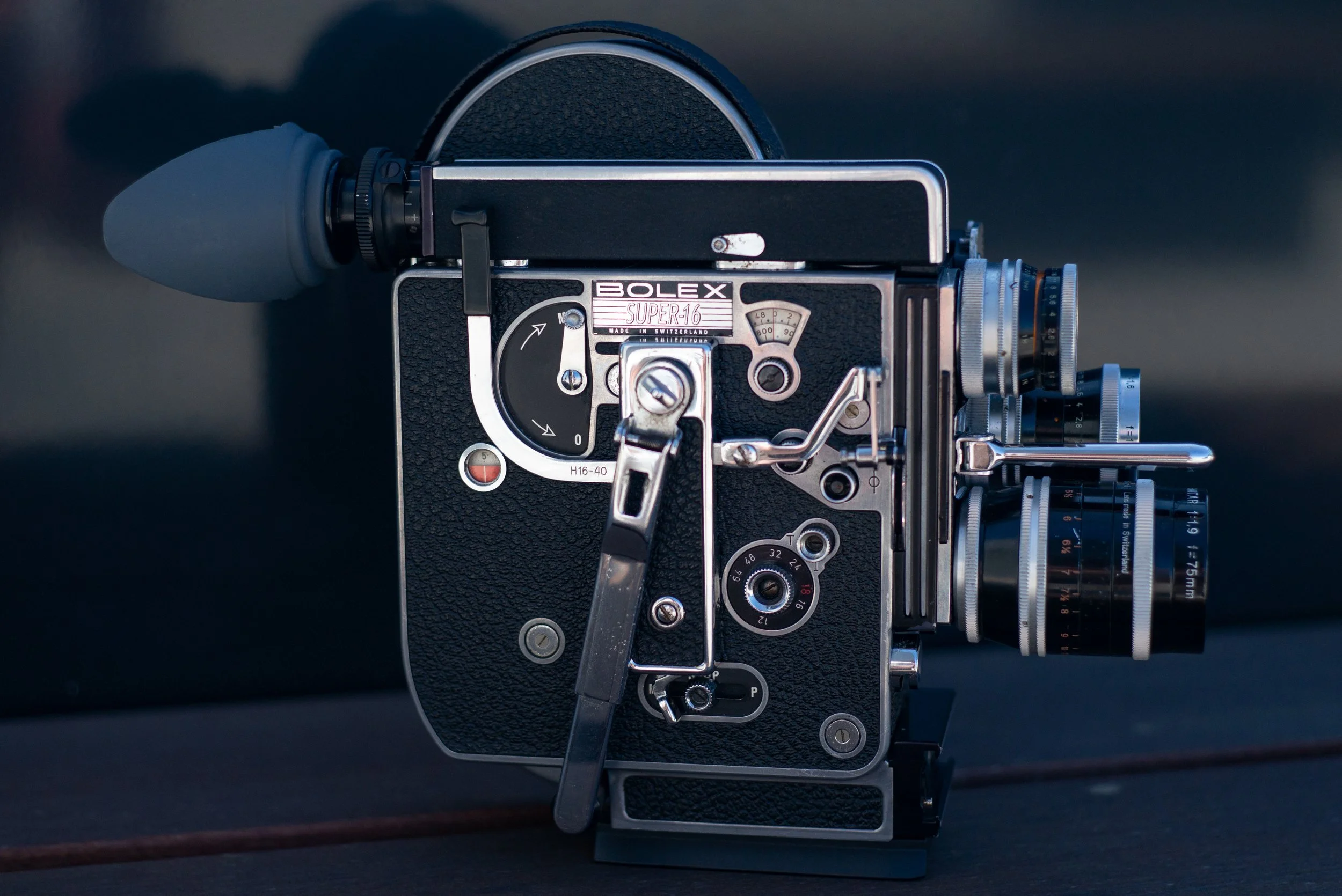 Close-up of a vintage Bolex Super 16 millimeter film camera with various adjustment dials and lenses.