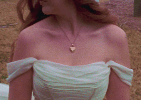 Close-up of a woman wearing an off-the-shoulder white dress and a heart-shaped necklace.