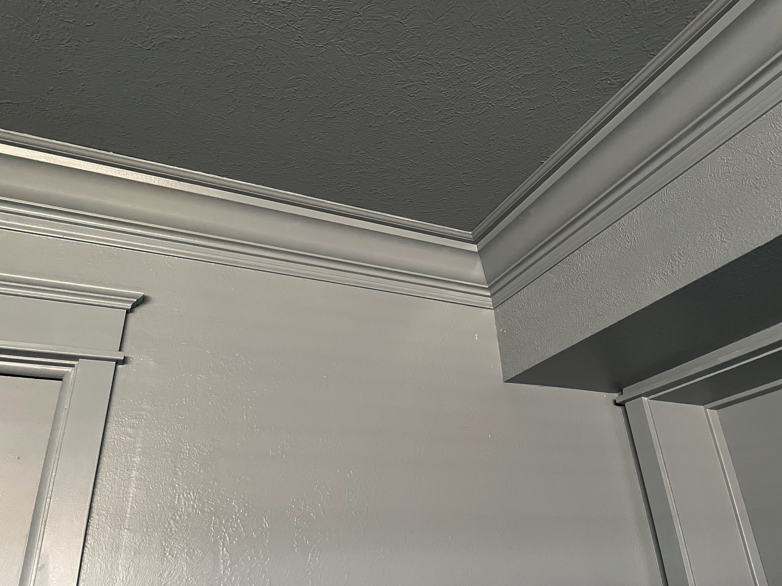 Close-up view of a ceiling with textured dark paint and crown molding, part of a room's interior architecture.
