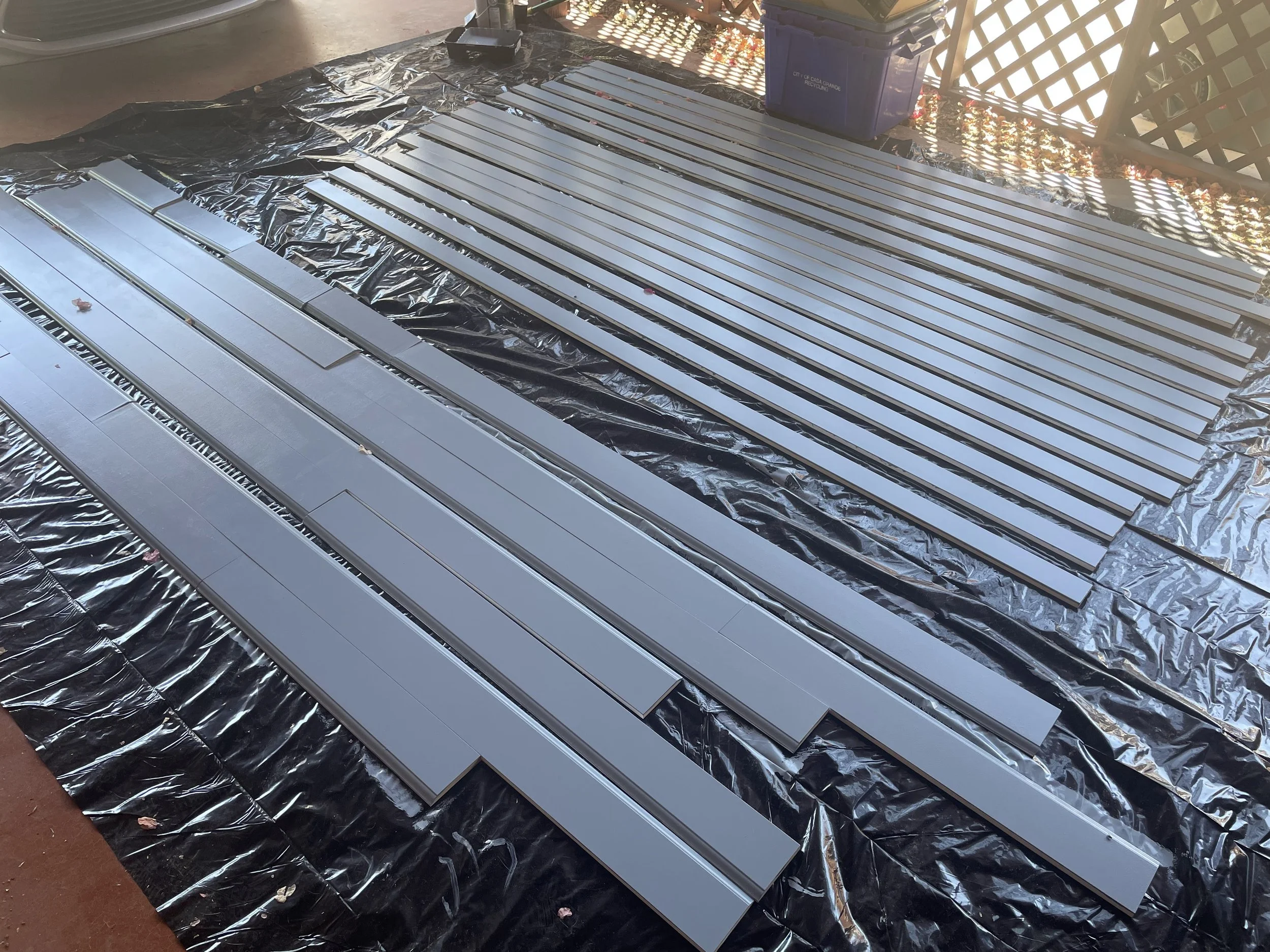 Wood trim pieces; baseboards, door casing and crown molding are laid out and painted in preperation for installation.