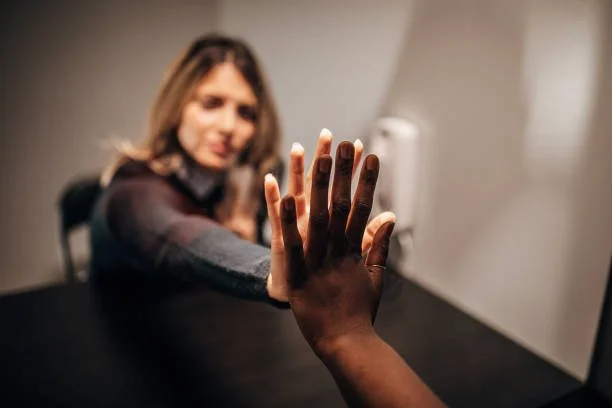 A woman reaching out her hand for a high-five with another person in an indoor setting.