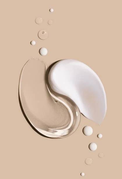 Two curved, semi-opaque gel-like blobs, one white and one beige, surrounded by small circular beads on a beige background.