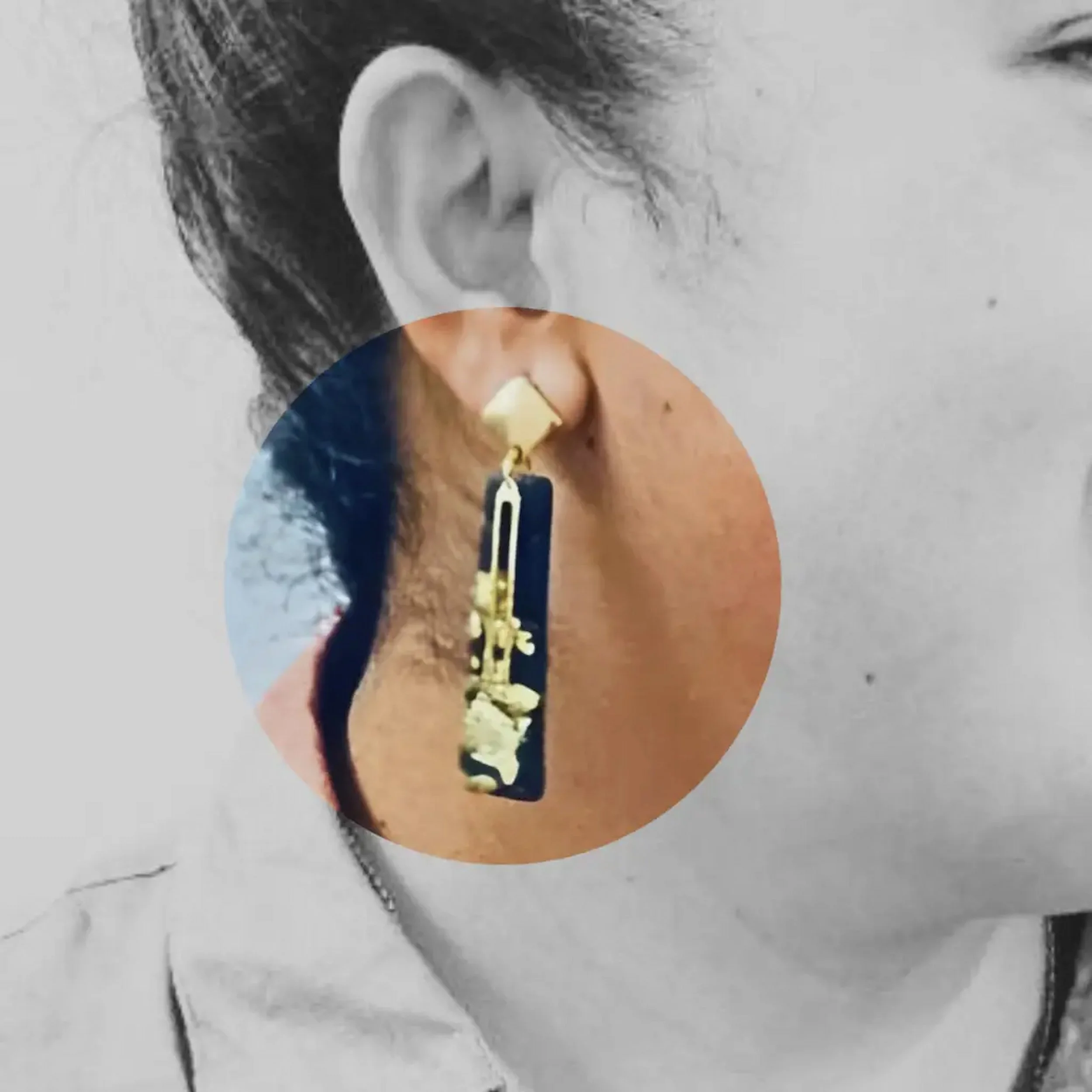 Close-up of a customers ear with an elaborate long gold and black earring, overlaid on a black-and-white photograph of the woman's face - Formal piece to standout.