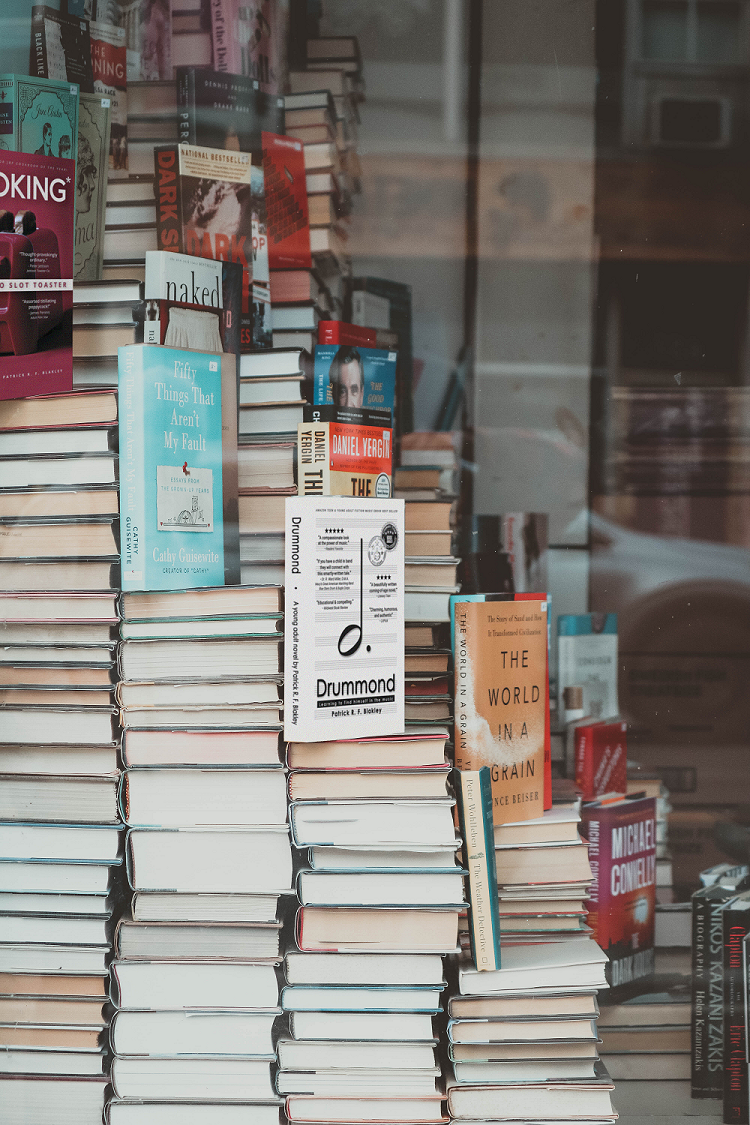 Stacks of books with one called Drummond Learning to find himself in the music and another called Cooking with a Two Slot Toaster.