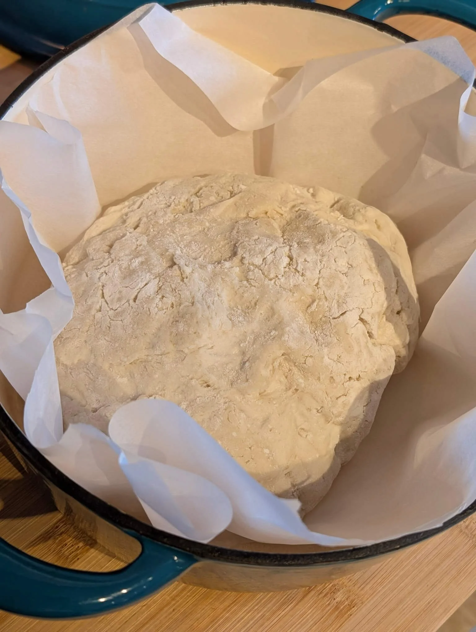 No-knead peasant bread dough in a parchment-lined Dutch oven, ready to bake