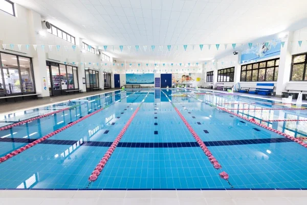 Indoor swimming pool with lane dividers, large windows, and blue and white decor.
