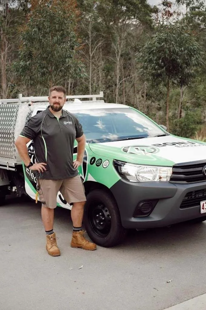 Bonus Electrical technician standing beside a company work vehicle, servicing the Gold Coast.