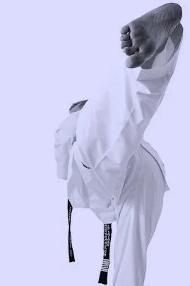 A person in a white martial arts gi executing a high kick, with their arm raised in a fist, against a plain light purple background.
