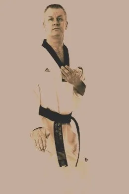 A person in a martial arts uniform with a black belt, standing in a fighting stance.