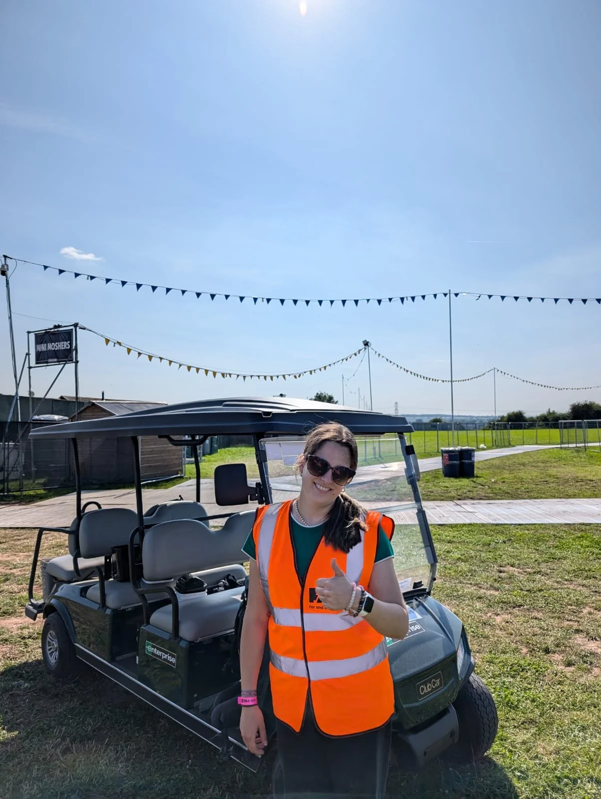 Event professional wearing a high-visibility vest on site at an outdoor event, smiling during event operations.