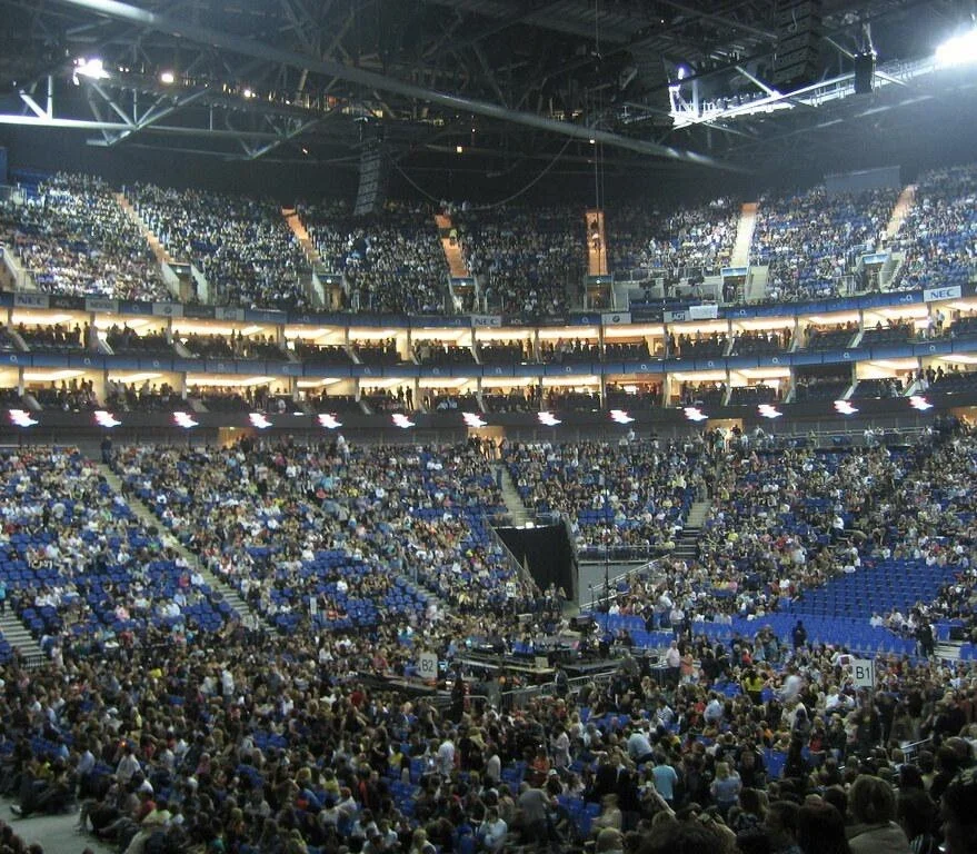 View of a packed indoor arena before a live performance, highlighting the scale of a large-scale event.