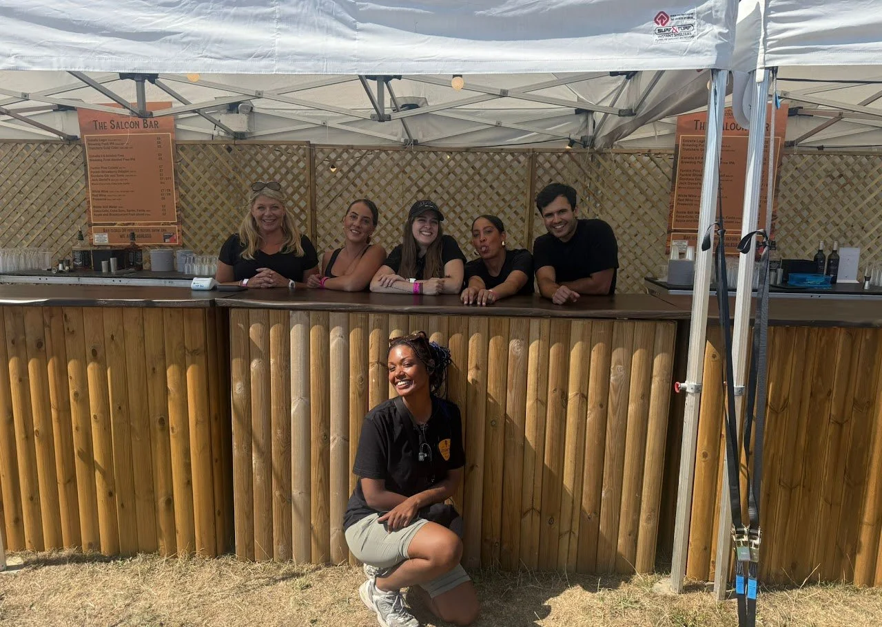 Festival bar team posing together after service, reflecting teamwork and collaboration during a busy event day.