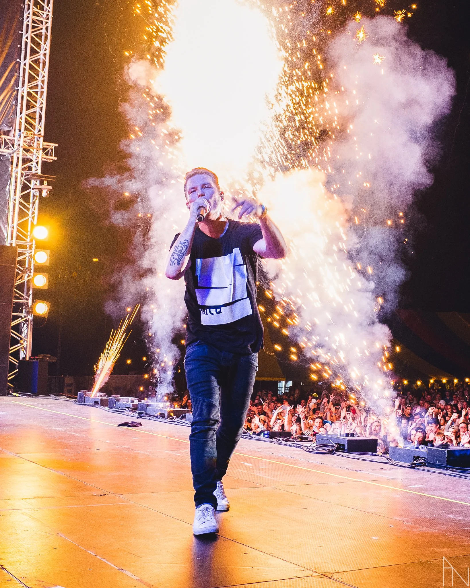 Mies esiintymässä lavalla, taustalla ilotulituksia ja juhlayleisöä. Cheek Jurassic Rock Mikkeli.