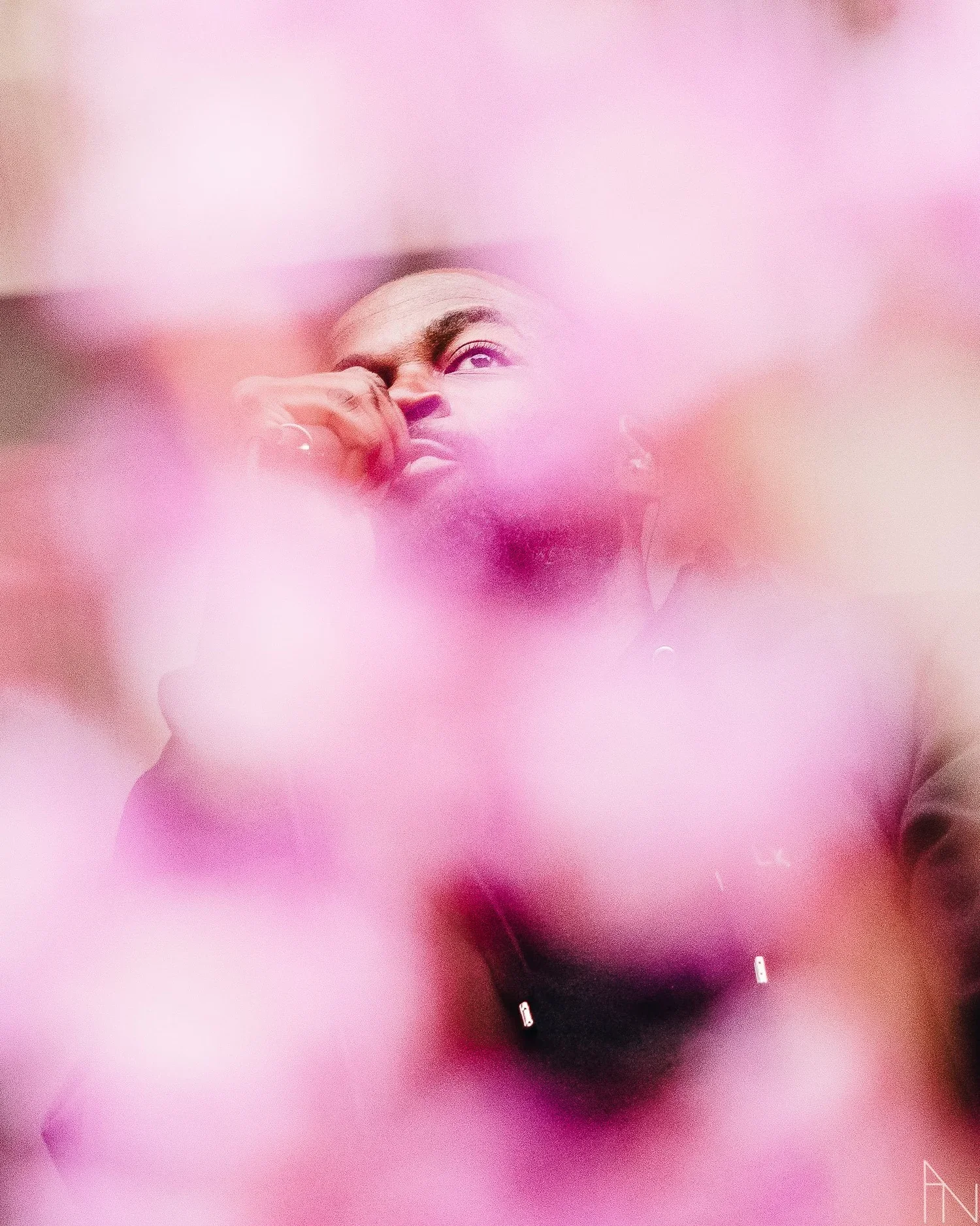 Henkilö tarkastelee jotain lähelle, kuvassa on vaaleanpunaisia ja vaaleanpunaisia ja vaaleanpunaisia epätarkkoja muotoja ympärillä.