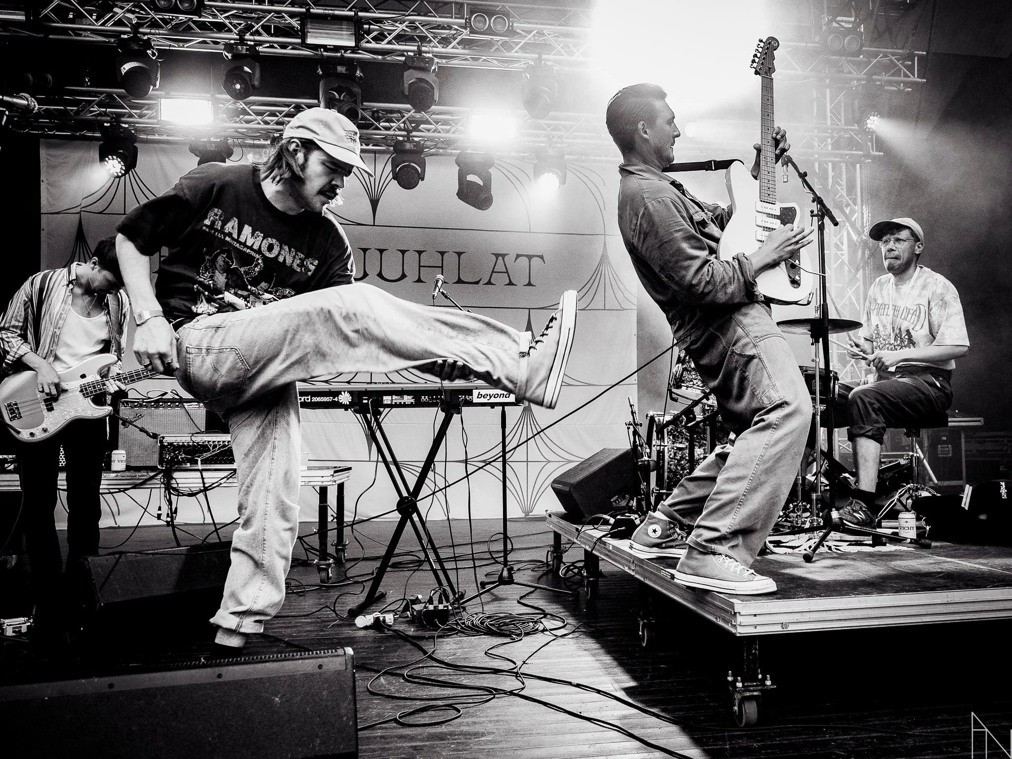 Musiikkiryhmä esiintyy lavalla, yksi jäsen tanssii tai tekee liikettä, muita soittavat instrumentteja. Arppa Puistojuhlat Jyväskylän Kesä.