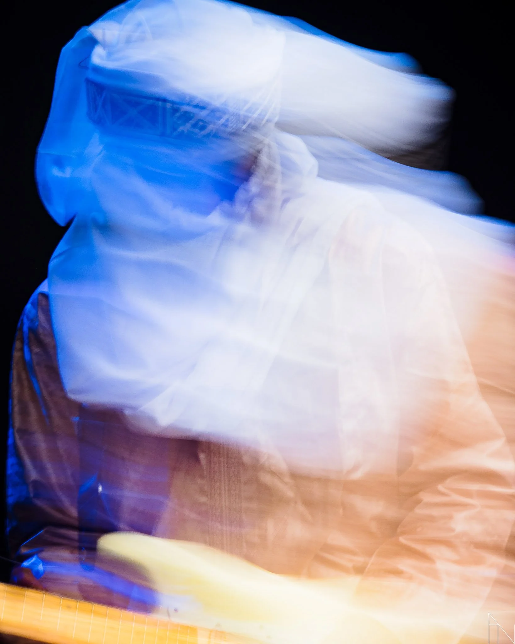 Hämärässä valaistuksessa oleva ihminen, liikkuvan kameran aiheuttama epätarkkuus ja värit, erityisesti sininen ja oranssi. Mdou Moctar Pori Jazz 2022.